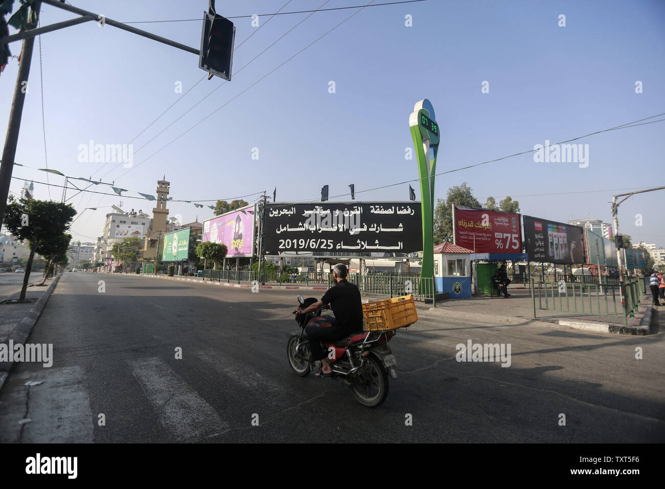 La città di Gaza, Territori palestinesi. Il 25 giugno, 2019. Un uomo palestinese spinge la sua motocicletta su strade vuote come i negozi chiusi durante uno sciopero generale contro gli Stati Uniti-sponsorizzato conferenza su lo sviluppo economico palestinese in Bahrain. La riunione di due giorni si propone di innalzare a 50 miliardi di dollari di investimenti in dieci anni, ma i leader palestinesi si sono rifiutati di partecipare è casting seri dubbi circa l'utilità dell'evento, chiamato la pace per la prosperità Workshop. Credito: Mohammed Talatene/dpa/Alamy Live News Foto Stock