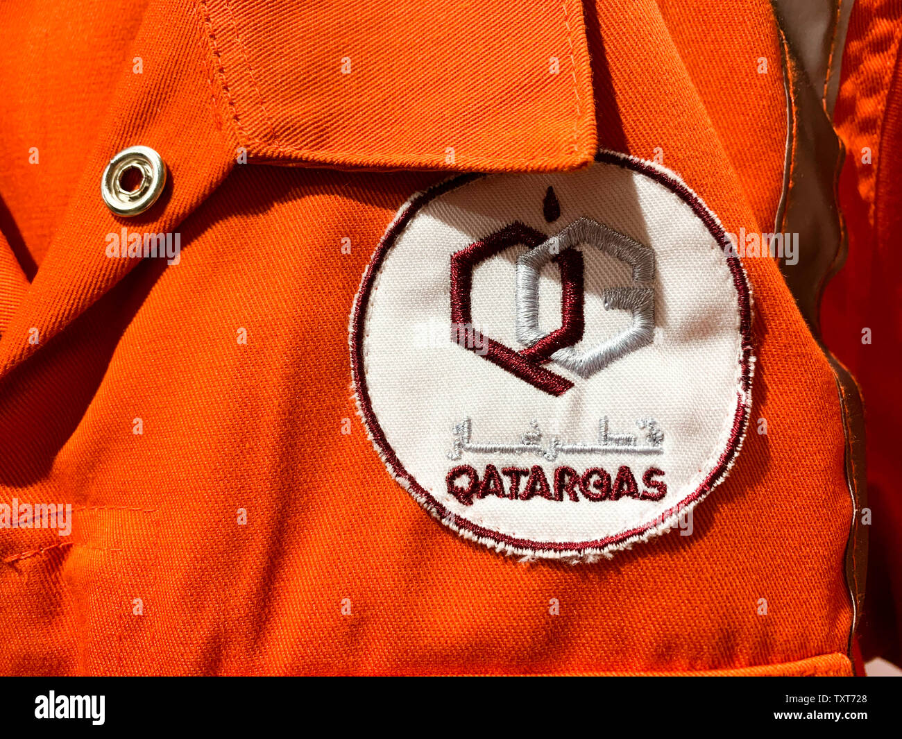 Indumenti da lavoro di colore arancione con logo in arabo e in inglese. Qatargas è il più grande del mondo di gas naturale liquefatto (GNL) dell'azienda. Aprile 2019, Doha/ Qatar. Foto Stock