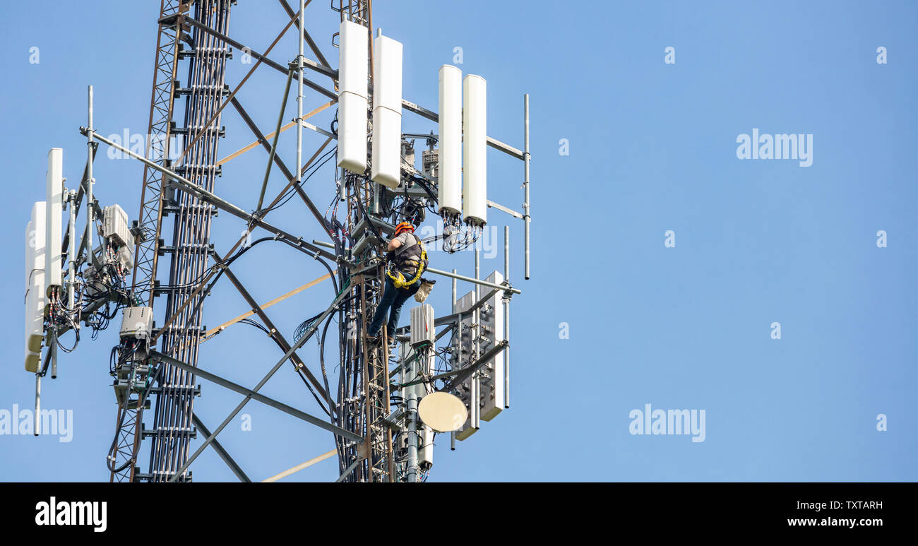 Comunicazione opere di manutenzione. Il tecnico arrampicata su telecom  antenna torre contro il cielo blu, sfondo spazio copia Foto stock - Alamy