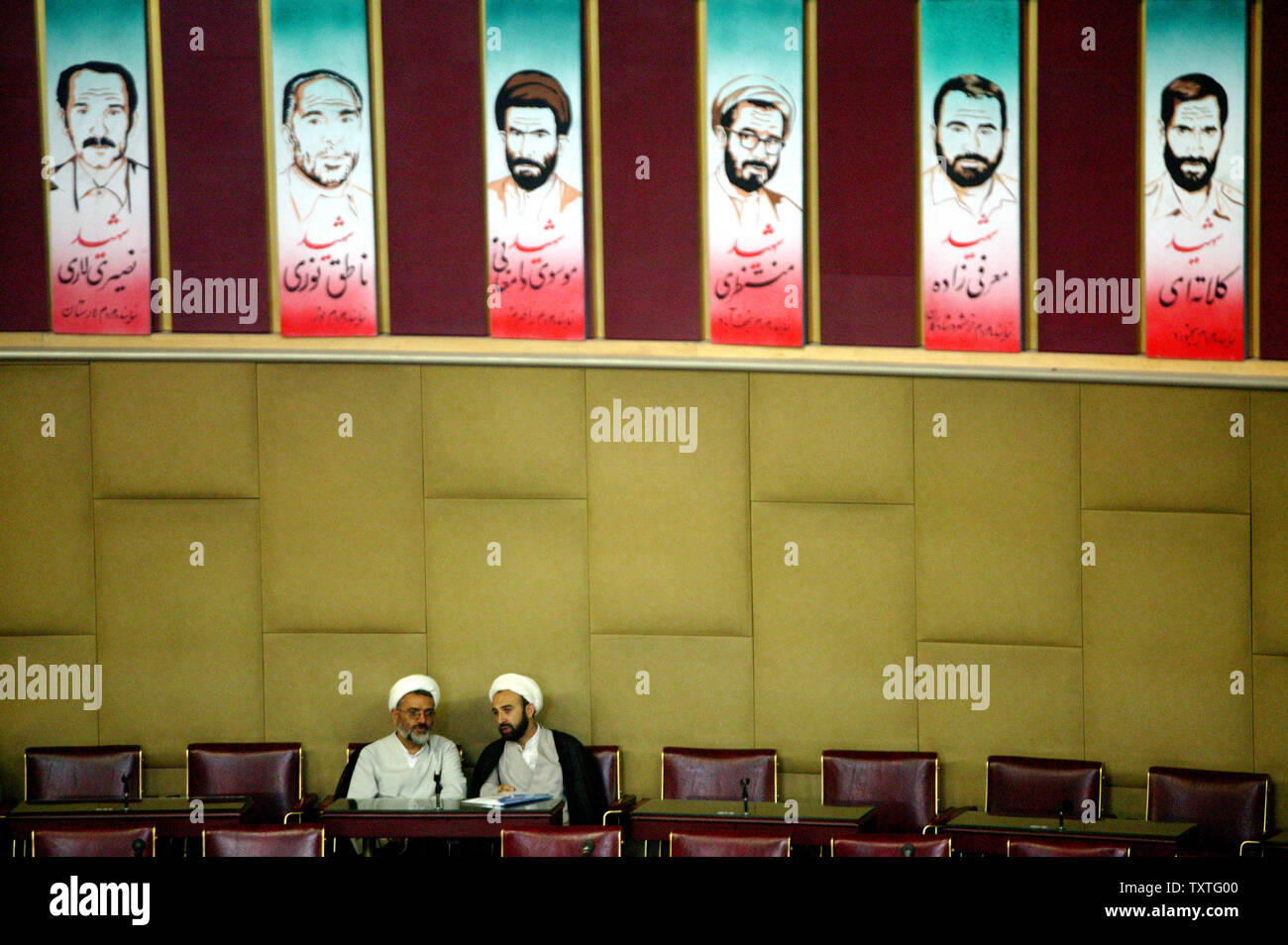 Top iraniane di ecclesiastici a sedersi sotto le foto dei membri del gruppo di esperti dei martiri come frequentano il primo giorno del gruppo di esperti in Iran il vecchio parlamento a Teheran il 26 agosto 2008. Il gruppo di esperti è un corpo clericale che elegge il capo supremo dell'Iran. (UPI foto/Mohammad Kheirkhah) Foto Stock