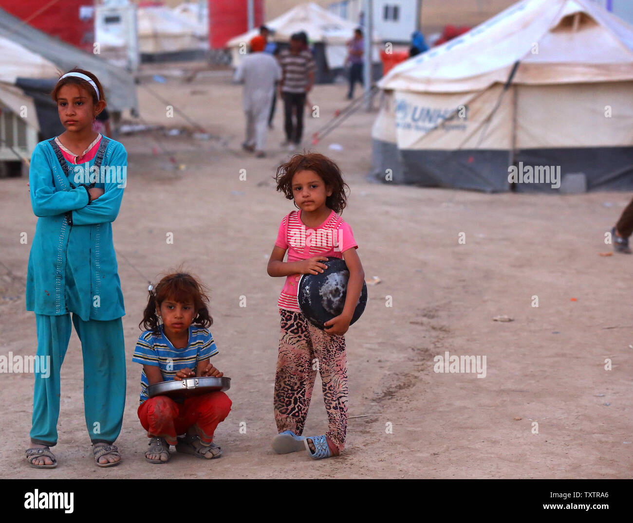 I rifugiati iracheni ragazze , che sono fuggiti dalle violenze a Mosul, attendere fino a ricevere gratuitamente il cibo durante il sacro mese di digiuno del Ramadan all'interno del Khazer campo profughi alla periferia di Arbil in Iraq le regione del Kurdistan, 29 giugno 2014.decine di migliaia di persone sono fuggite in Iraq della seconda più grande città di Mosul dopo che essa è stata invasa da ISIS (Stato islamico dell Iraq e Siria) militanti. Molti sono stati temporaneamente alloggiato in diversi campi di sfollati interni attorno alla regione compresa la zona vicino a Erbil, come essi sperano di immettere la sicurezza della vicina regione curda. UPI/Ceerwan Aziz Foto Stock