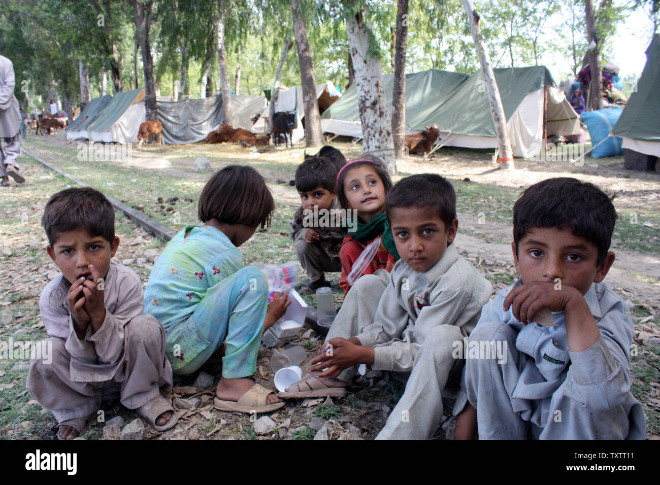 Bambini curiosi sedersi e guardare in un campo di rifugiati in Mardan due, Pakistan, come residenti fuggire da Mingora, la principale città del Pakistan travagliato della valle di Swat, il 11 maggio 2009. Circa 360.000 persone hanno lasciato la travagliata regione come la lotta continua fra l esercito pakistano e i Talebani. (UPI foto/Sajjad Ali Qureshi) Foto Stock