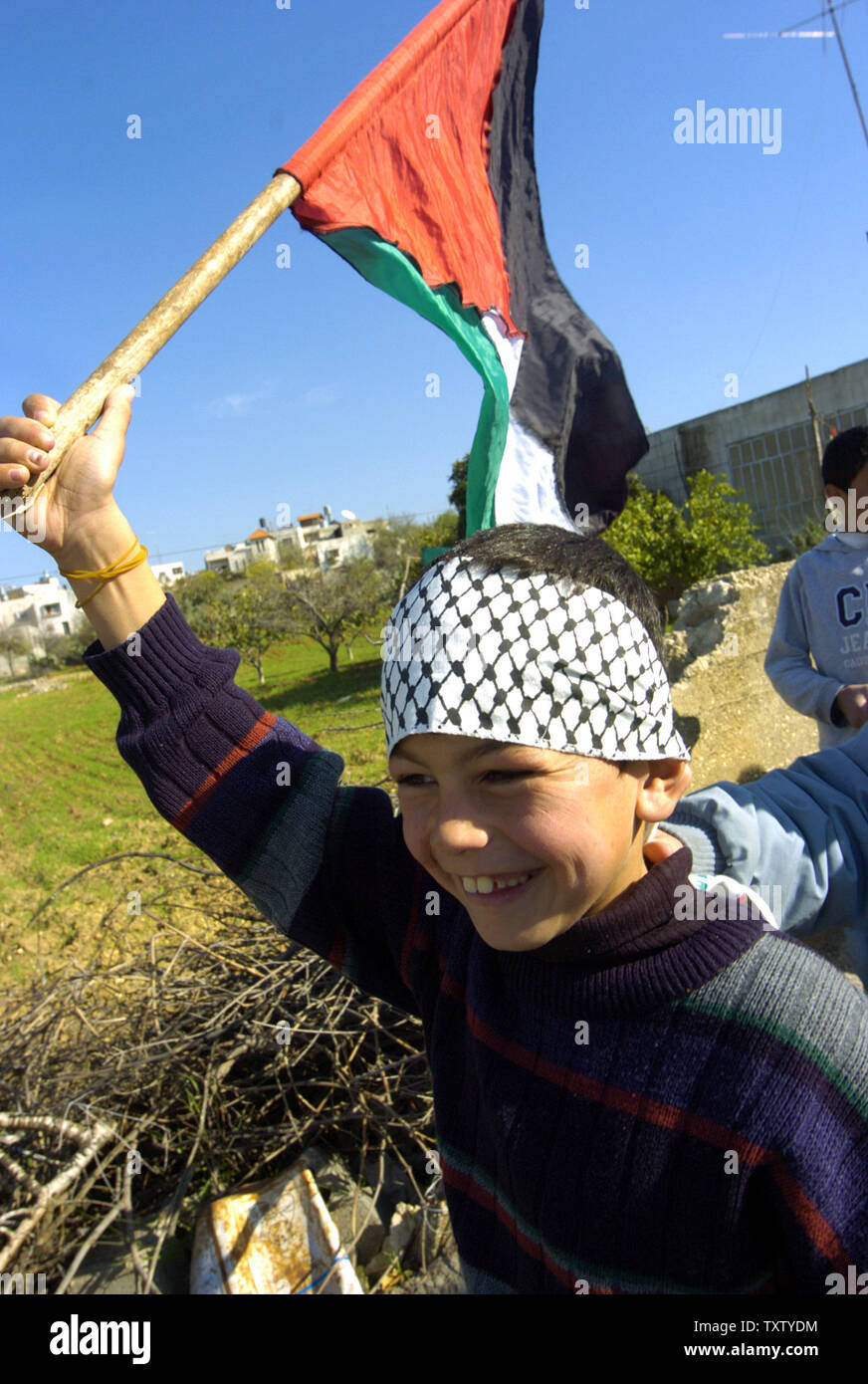 Un ragazzo palestinese porta una bandiera a una protesta contro la separazione israeliano muro in Cisgiordania villaggio di Bil'in, a ovest di Ramallah, Dicembre 27, 2004. (UPI foto/Debbie Hill) Foto Stock