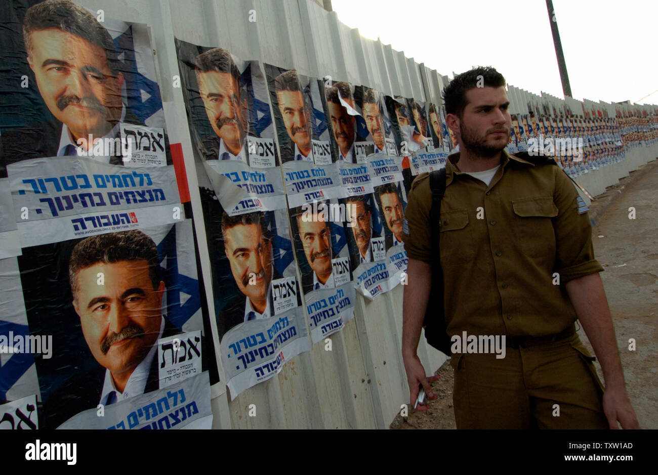 Un soldato israeliano da passeggiate campain poster del leader del partito laburista Amir Peretz, in Tel Aviv il 26 marzo 2006. Gli israeliani faranno capo a sondaggi su Martedì, 28 marzo per un'elezione generale. (UPI foto/Debbie Hill) Foto Stock