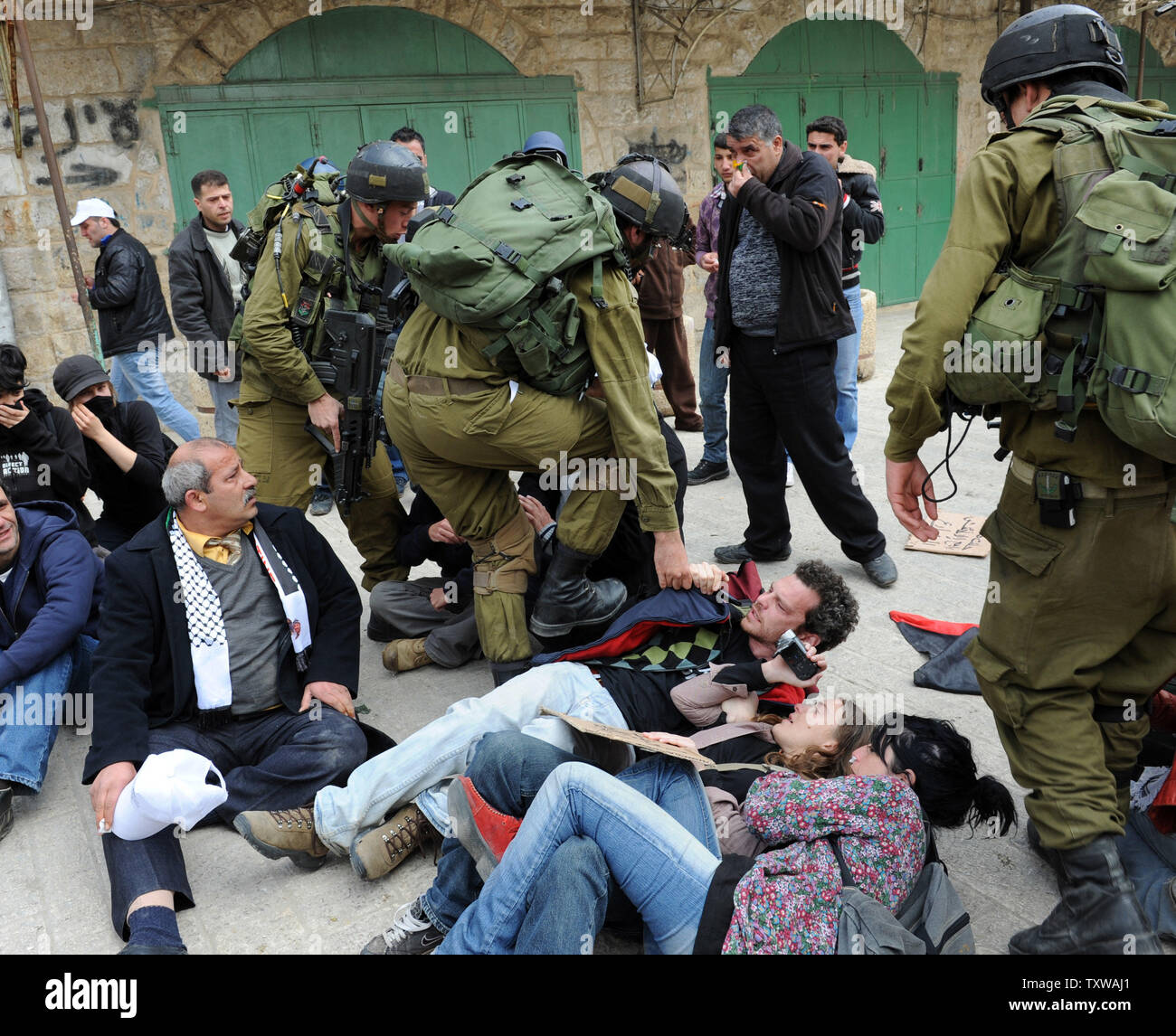 Soldati israeliani azzuffa con attivisti internazionali durante una manifestazione di protesta contro la chiusura di Shuhada Street ai palestinesi a Hebron, West Bank, 25 febbraio 2011. Manifestanti hanno gridato slogan contro gli Stati Uniti per vetoing la risoluzione del Consiglio di Sicurezza delle Nazioni Unite che condanna gli insediamenti israeliani. UPI/Debbie Hill. Foto Stock