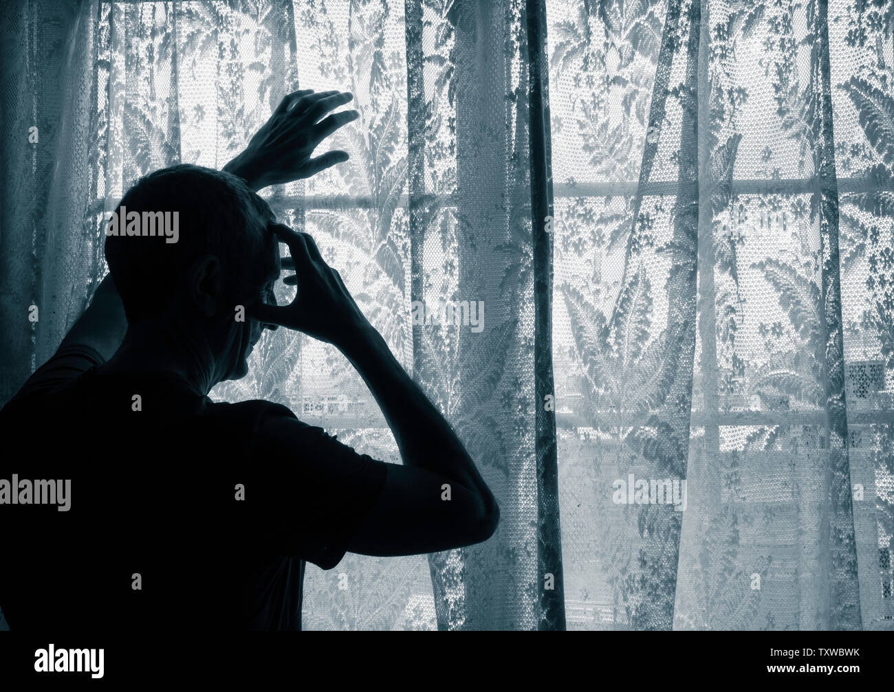 Uomo maturo con la mano sulla testa vicino alla finestra. Concetto di immagine per la depressione, depressione maschio, salute mentale, maschio suicida... Foto Stock