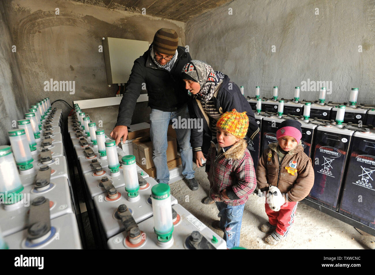 Palestinesi controllare le batterie che immagazzinano energia alimentate da turbine eoliche e pannelli solari in She'b El-Buttum villaggio nel sud delle colline di Hebron, West Bank, febbraio 29, 2012. Il popolo israeliano di amministrazione civile ha emesso ordini di demolizione per le energie rinnovabili impianti a pannelli solari e turbine a vento che forniscono elettricità ai palestinesi che Israele si rifiuta di gancio fino alla rete elettrica. Le installazioni di energia sono stati pagati dal Ministero tedesco degli Affari Esteri e avviato da volontari israeliani. L'energia elettrica prodotta da pannelli solari e turbine eoliche ha revoluti Foto Stock
