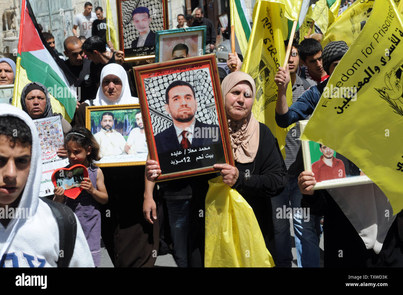 Palestinesi portare le foto di parenti imprigionato durante una manifestazione di protesta in solidarietà con i palestinesi detenuti nei prigionieri israeliani su prigionieri' giorno nella città biblica di Betlemme, West Bank, 17 aprile 2012. Circa 1.200 prigionieri palestinesi nelle carceri israeliane ha iniziato uno sciopero della fame a tempo indeterminato oggi come un altro 2.300 ha rifiutato il cibo per un giorno. Ci sono circa 4.700 i palestinesi nelle carceri israeliane. UPI/Debbie Hill Foto Stock