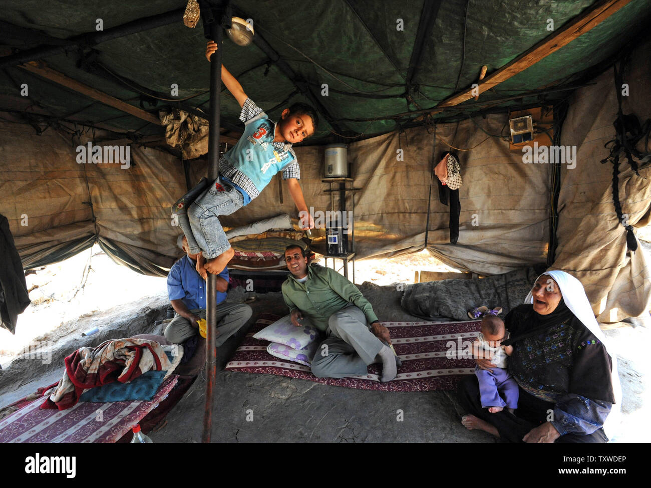 Mohammad palestinese Nawaagah si arrampica la pole nel suo nonno la tenda nel villaggio di Susya nel sud delle colline di Hebron, West Bank, 17 giugno 2012. Il popolo israeliano di amministrazione civile ha emesso circa 50 ordini di demolizione su Giugno 12, per l'intero villaggio di Susya, comprese le case, capanne, tende e strutture agricole dopo Regavim, un israeliano a destra dell' organizzazione ha presentato una petizione al Tribunale per la completa demolizione di Susya. I palestinesi di Susya vengono spesso attaccati da estrema di coloni ebrei che vivono nelle vicinanze. UPI/Debbie Hill Foto Stock