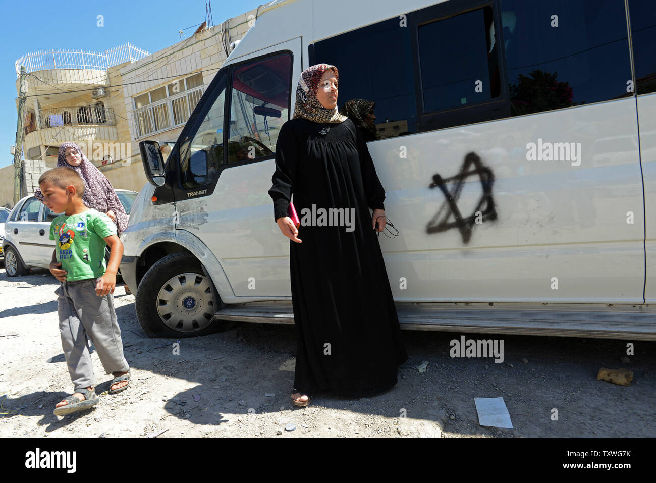 Palestinesi sostare nelle vicinanze di un veicolo con pneumatici drasticamente ridotto e una stella di Davide spruzzata sul lato in un sospetto di 'Prezzo' attacco da parte della destra di ebrei, di Beit Hanina, Israele, Giugno 24, 2013. I pneumatici erano stracciati su 21 veicoli e una stella di Davide spruzzato su un furgone per una notte nella quarta sospetta prezzo 'Tag' attentato in un mese. Il Primo Ministro israeliano Benjamin Netanyahu detto tali crimini di stampo nazionalistico contro gli Arabi andare contro i valori del giudaismo e Israele. UPI/Debbie Hill Foto Stock