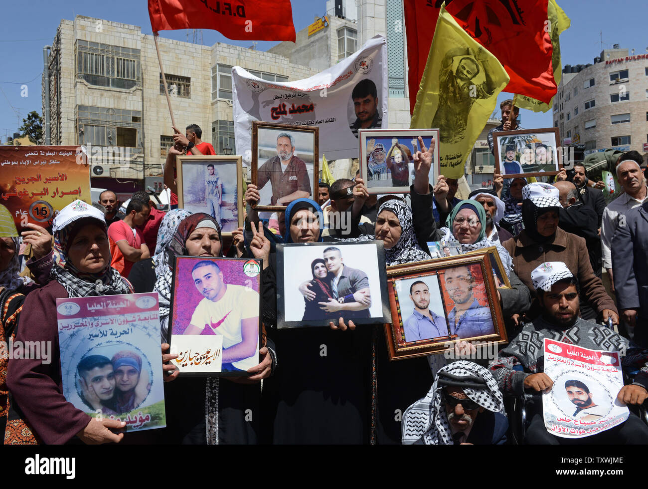 Palestinesi tenere le foto dei membri della famiglia tenutasi a prigionieri israeliani durante una manifestazione di protesta sul prigioniero palestinese giorno a Ramallah in Cisgiordania, 17 aprile 2014. Secondo palestinese a gruppi per la difesa dei diritti umani non ci sono più di 5 mila palestinesi nelle carceri israeliane. I funzionari palestinesi chiedono che Israele rilascia il quarto gruppo di prigionieri al fine di estendere i colloqui di pace passato il mese di aprile 29 scadenza. UPI/Debbie Hill Foto Stock