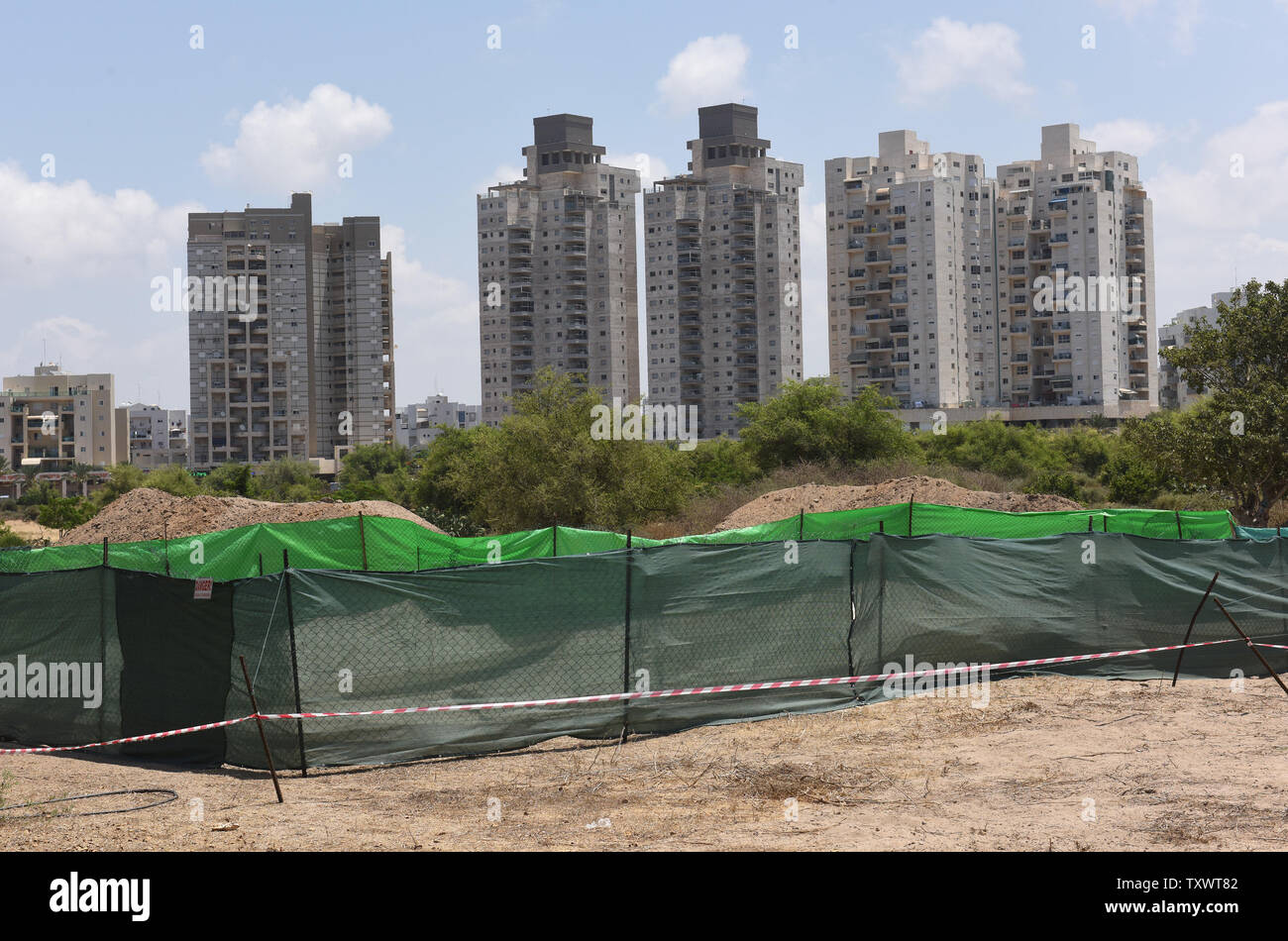 Appartamento israeliano edifici a stare dietro la coperta area di scavo di una rivoluzionaria scoperta del primo cimitero Filisteo trovata nel porto della città di Ashkelon, Israele, 28 giugno 2016. I Filistei erano noti come la archenemy dell antico Israele dalla Bibbia ebraica.La scoperta è il risultato di oltre trenta anni di scavi alla vista che sono stati effettuati mediante il prelievo di Leon spedizione in Ashkelon. Conclusioni dal cimitero, datata al XI - VIII secolo a.e.v., possono supportare la rivendicazione registrati nella Bibbia che i Filistei erano migranti sulle rive dell antico Israele wh Foto Stock