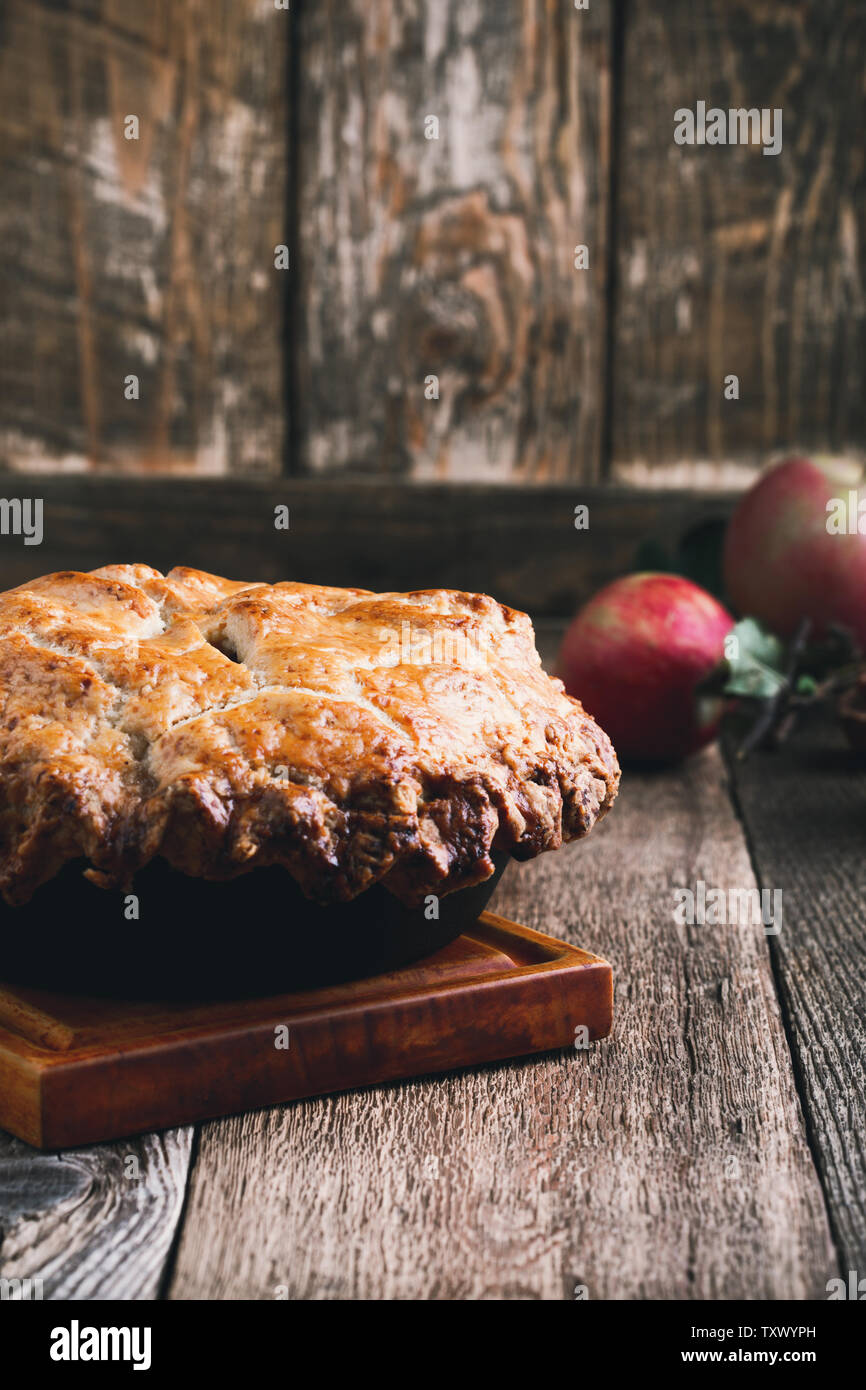 La torta di mele in padella in ghisa, tradizionale dessert di ringraziamento, autunno accogliente piatto rurale sul tavolo di legno, vicino il fuoco selettivo Foto Stock