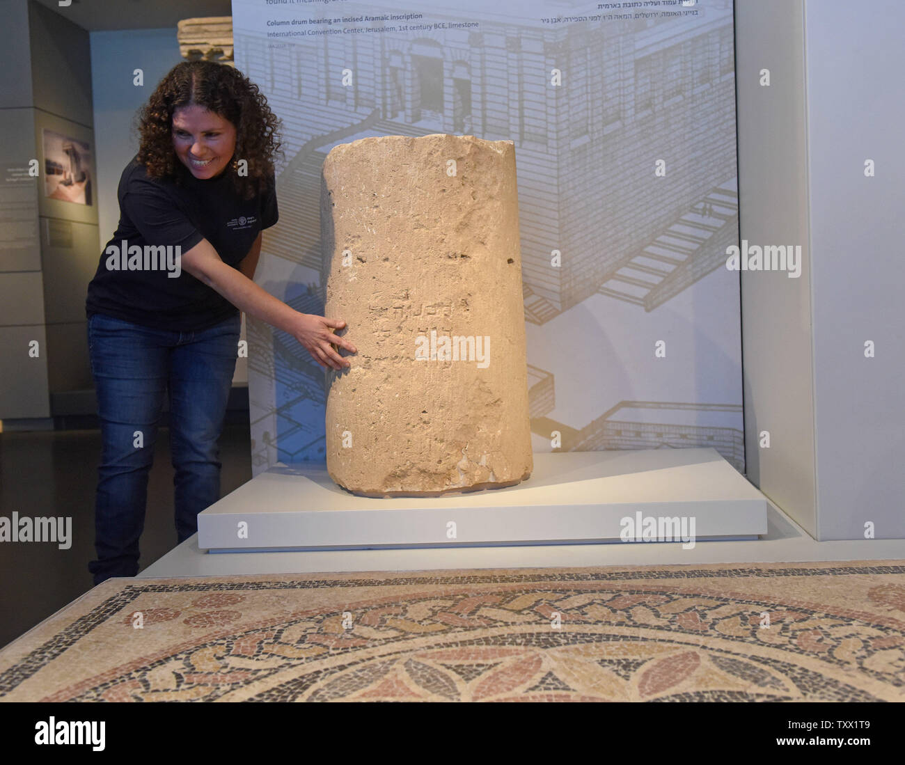 Prelievo Danit, Israeliano antichità autorità responsabile di scavo, tocca la colonna di pietra di tamburo con un duemila anni iscrizione in pietra, risalente all'epoca del Secondo Tempio (primo secolo CE), presentato dalle autorità di Antichità Israele e il Museo di Israele in occasione di una conferenza stampa presso il Museo di Israele a Gerusalemme, 9 ottobre 2018. L'unica iscrizione è il primo a mostrare il pieno controllo ortografico di Gerusalemme, è stato rinvenuto a Gerusalemme durante uno scavo, prima della costruzione di una nuova strada. La colonna di pietra tamburo, riutilizzata nella struttura romana, scritto in lettere ebraiche tipiche del secondo Foto Stock