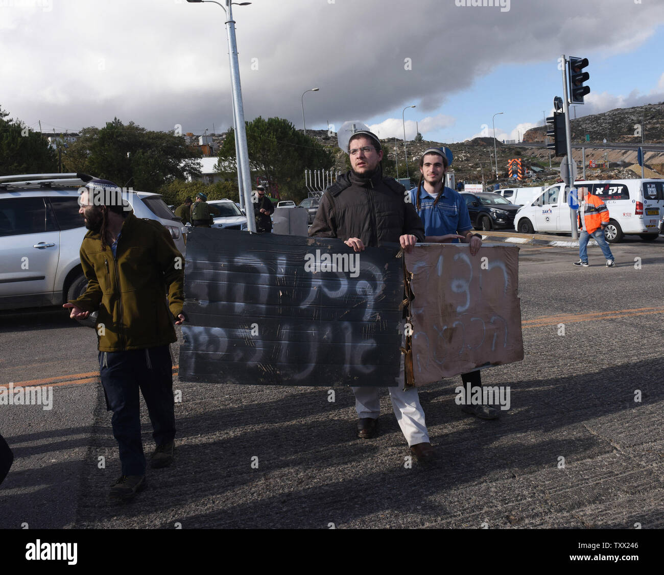 I coloni israeliani portano i segni la lettura 'ebraica il sangue non è versato invano" presso il sito dove un pistolero palestinesi uccisi due soldati israeliani e gravemente feriti due ulteriori, in un'unità da sparare a una fermata dell'autobus fuori dell'Givat Assaf avamposto, vicino a Ramallah in Cisgiordania, Dicembre 13, 2018. Il pistolero sbarcò il suo veicolo, ha aperto il fuoco e sono fuggiti dalla scena. L'esercito israeliano ha messo una chiusura a Ramallah e sta cercando per il tiratore. Foto di Debbie Hill /UPI Foto Stock