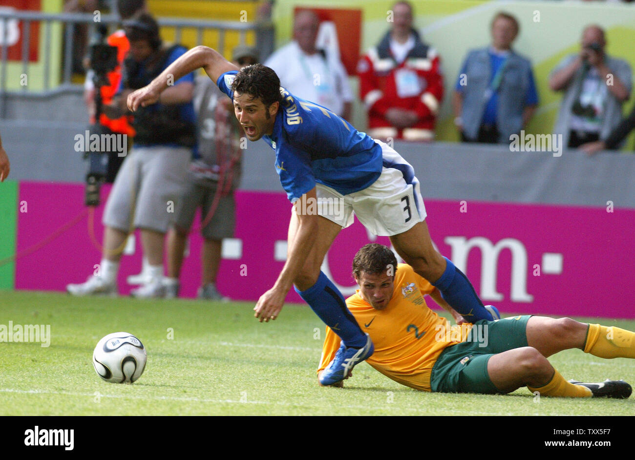 Italia di Fabio Grosso (3) scende al di sopra dell'Australia Luca Neill (2) sul suolo con un gioco che ha visto arbitro spagnolo Luis Medina Cantalejo aggiudicazione di un calcio di rigore in Coppa del Mondo di calcio a Kaiserslautern, in Germania il 26 giugno 2006. L'Italia ha eliminato l'Australia da World Cup concorrenza 1-0. (UPI foto/Arthur Thill) Foto Stock