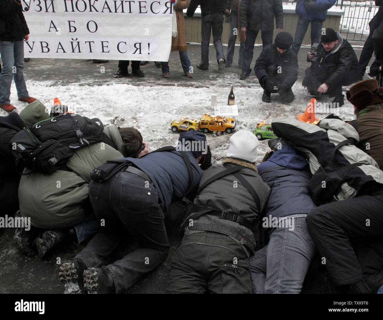 Fotografi di scattare foto di automobili giocattolo, bruciato dagli attivisti della gioventù ucraine Bratstvo gruppo (Fratellanza) di fronte all'ambasciata francese a Kiev il 8 febbraio 2006. I membri di Bratstvo protestare contro un cartoon di Gesù Cristo, pubblicato in France Soir, e la richiesta di scuse dal governo francese. (UPI foto/Sergey Starostenko) Foto Stock