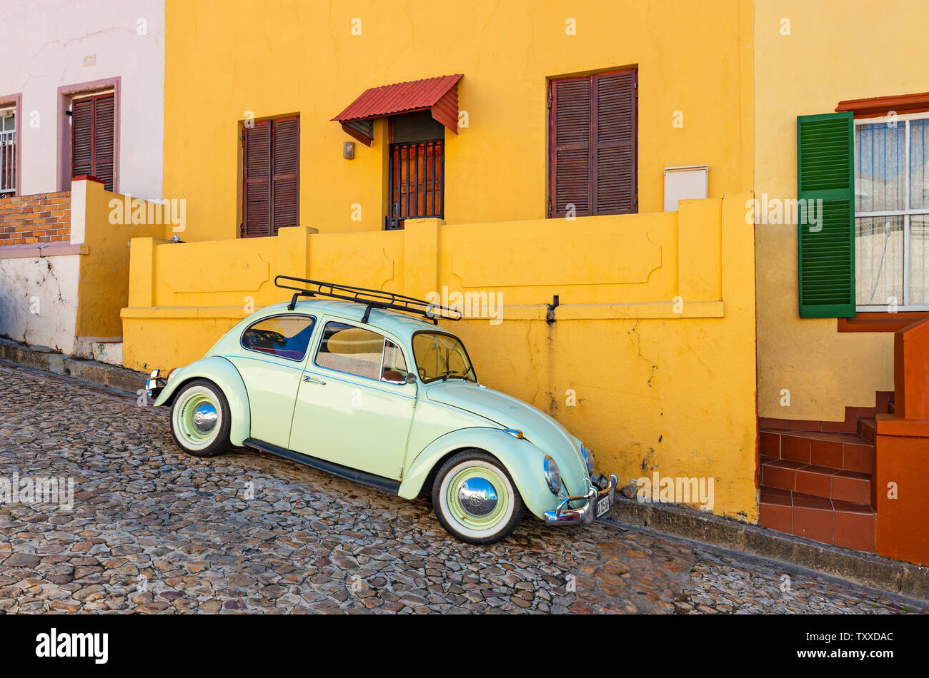 Una vecchia auto d'epoca ristrutturata o un vecchio timer in una strada colorata con facciata arancione del quartiere di Bo Kaap a Città del Capo, Sud Africa. Foto Stock