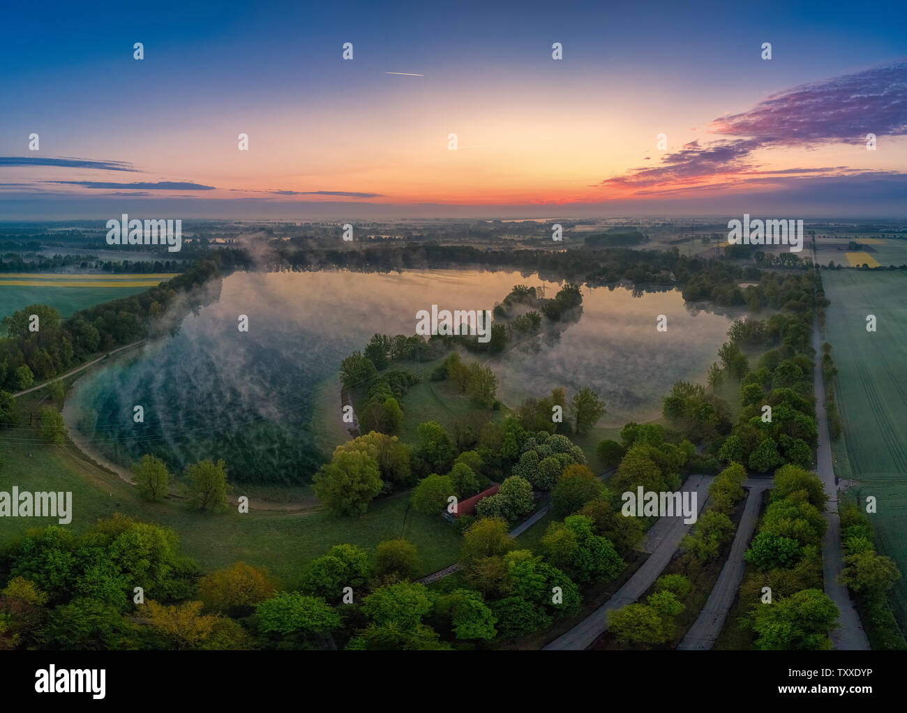 L'alba è appannata al mattino presto in un lago Foto Stock