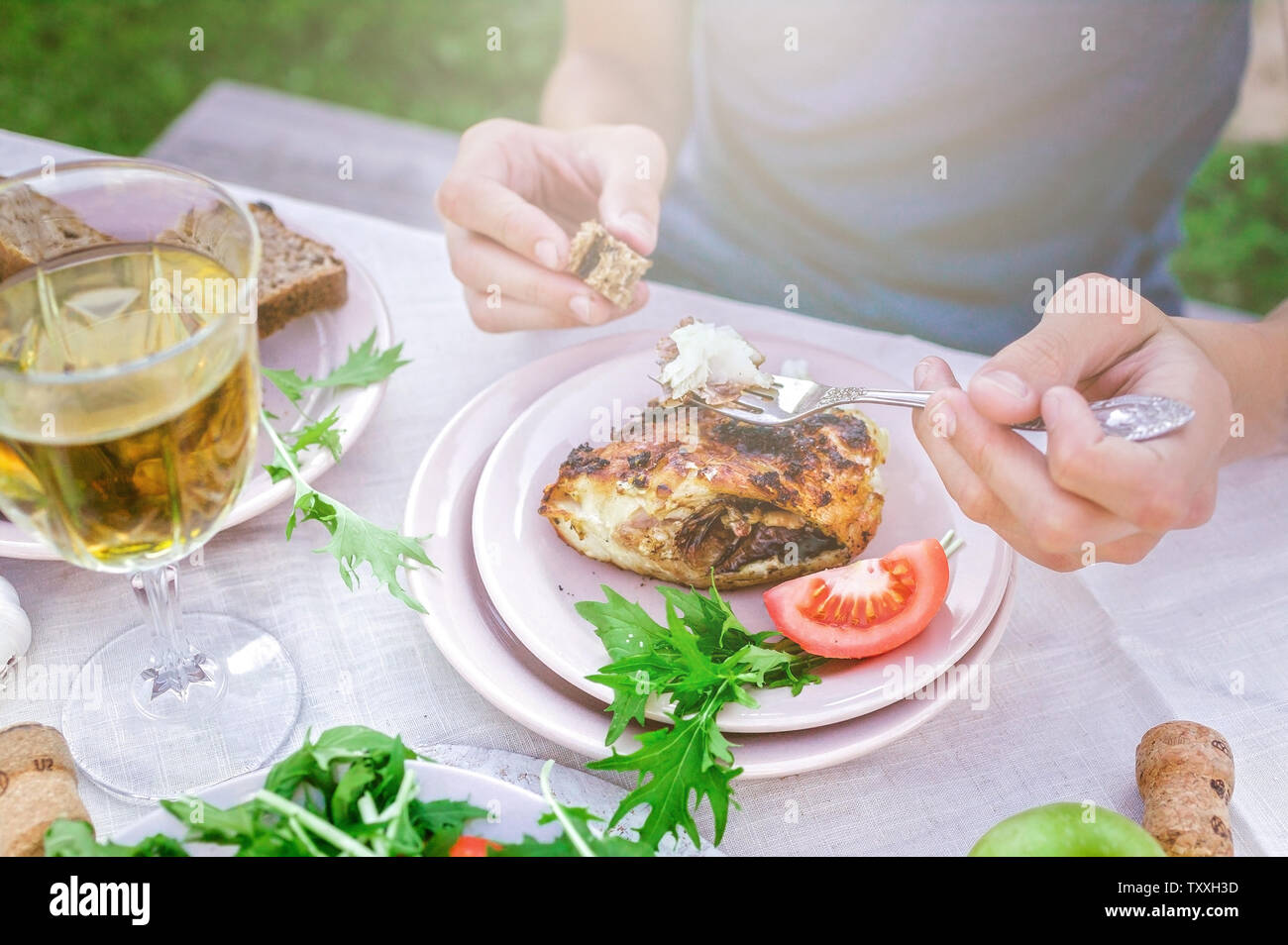 Uomo di mangiare fritture di pesce di mare in giardino a tavola. Concetto di cena con vino in aria fresca. Pesce e insalate di verdure ed erbe aromatiche. Mediterran Foto Stock