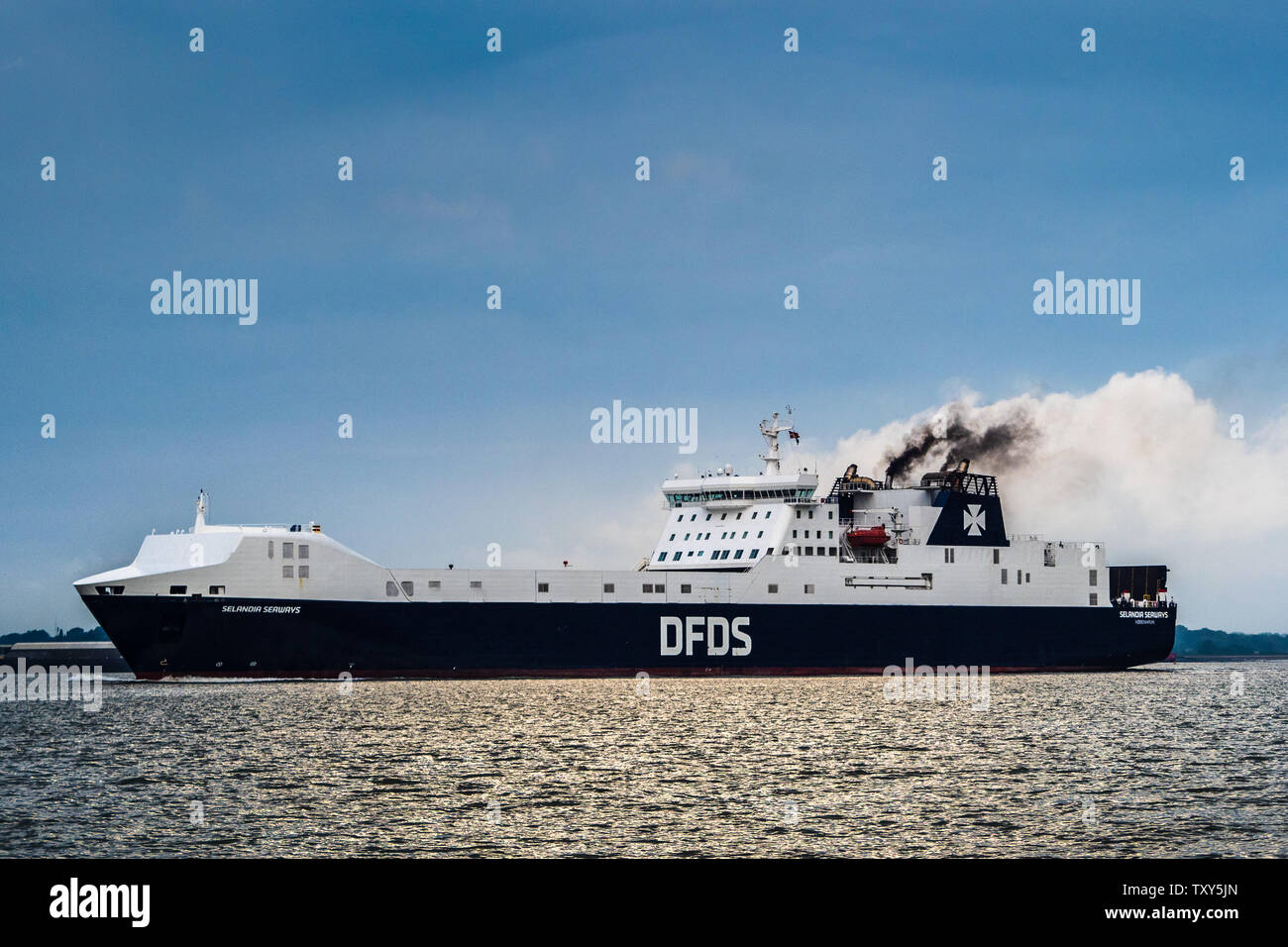 Spedizione di inquinamento atmosferico - diesel fumo emesso da un traghetto DFDS lasciando Felixstowe Port Regno Unito è accentuata dalle nuvole bianche dietro Foto Stock