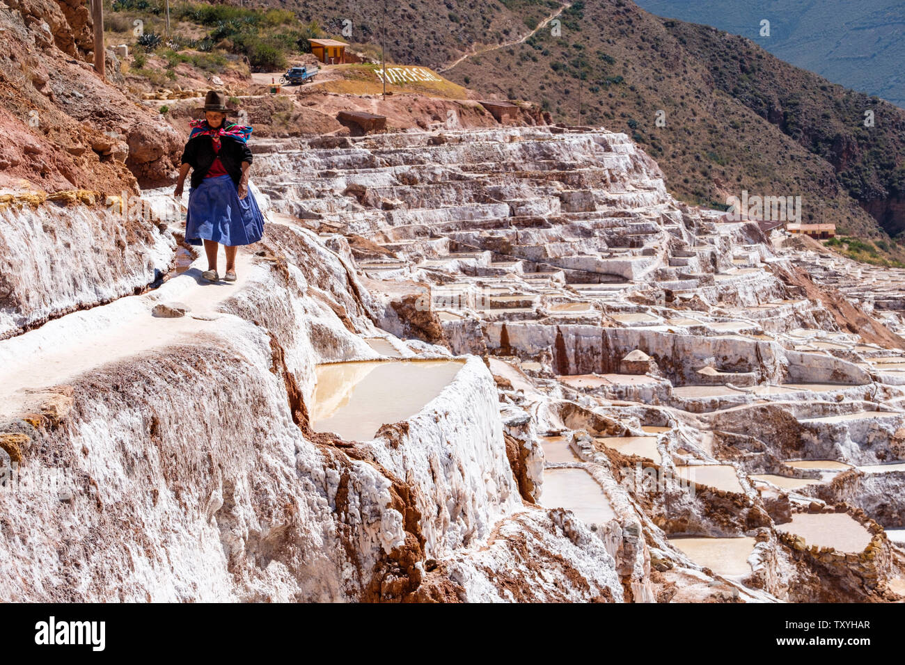 Locale Donna Peruviana a piedi su Salineras de Maras / Maras Miniere di Sale. Estrazione del sale a Maras saline, terrazze e stagni, Perù Valle Sacra. Foto Stock