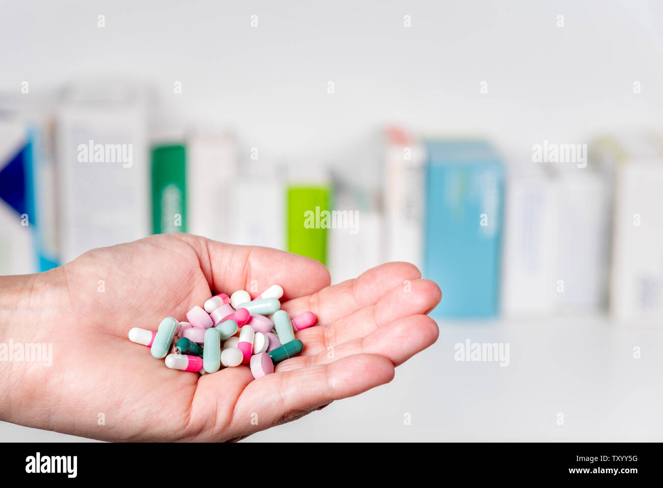 Mano piena di pillole e capsule con medidice pacchi in background. Messa a fuoco selettiva. Concetto di salute e medicina. Foto Stock