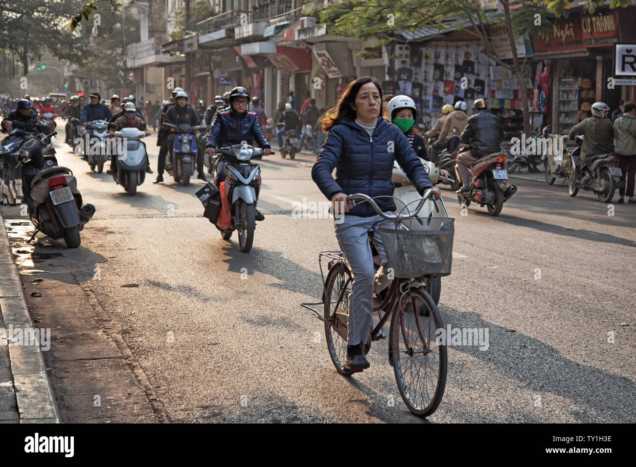 Hanoi, Vietnam - 23 dicembre 2013: il traffico intenso di scooter e biciclette su una strada di Hanoi con una donna in sella ad una bicicletta in primo piano Foto Stock