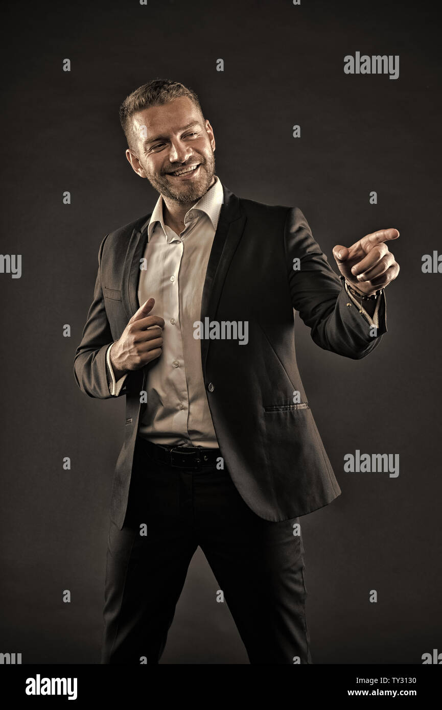 Uomo con un grande sorriso sul volto isolato su sfondo nero. Ragazzo con  tre giorni di barba smart indossare tuta e camicia bianca. Il comico  facendo prestazioni, concetto di divertimento. Addetto ufficio