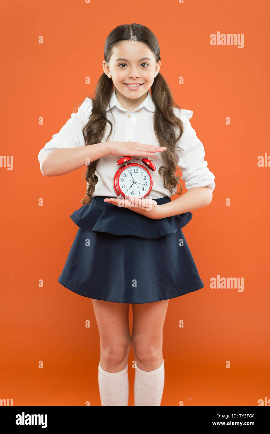 Scuola elementare campana giorno pianificazione. Concetto Schooltime. Schoolgirl bambino uniforme formale di tenere premuto il tasto alarm clock. Il tempo di studio. Le lezioni cominciano. Sviluppare la disciplina. Tempo di pausa e di relax. Tempo di vacanza. Foto Stock