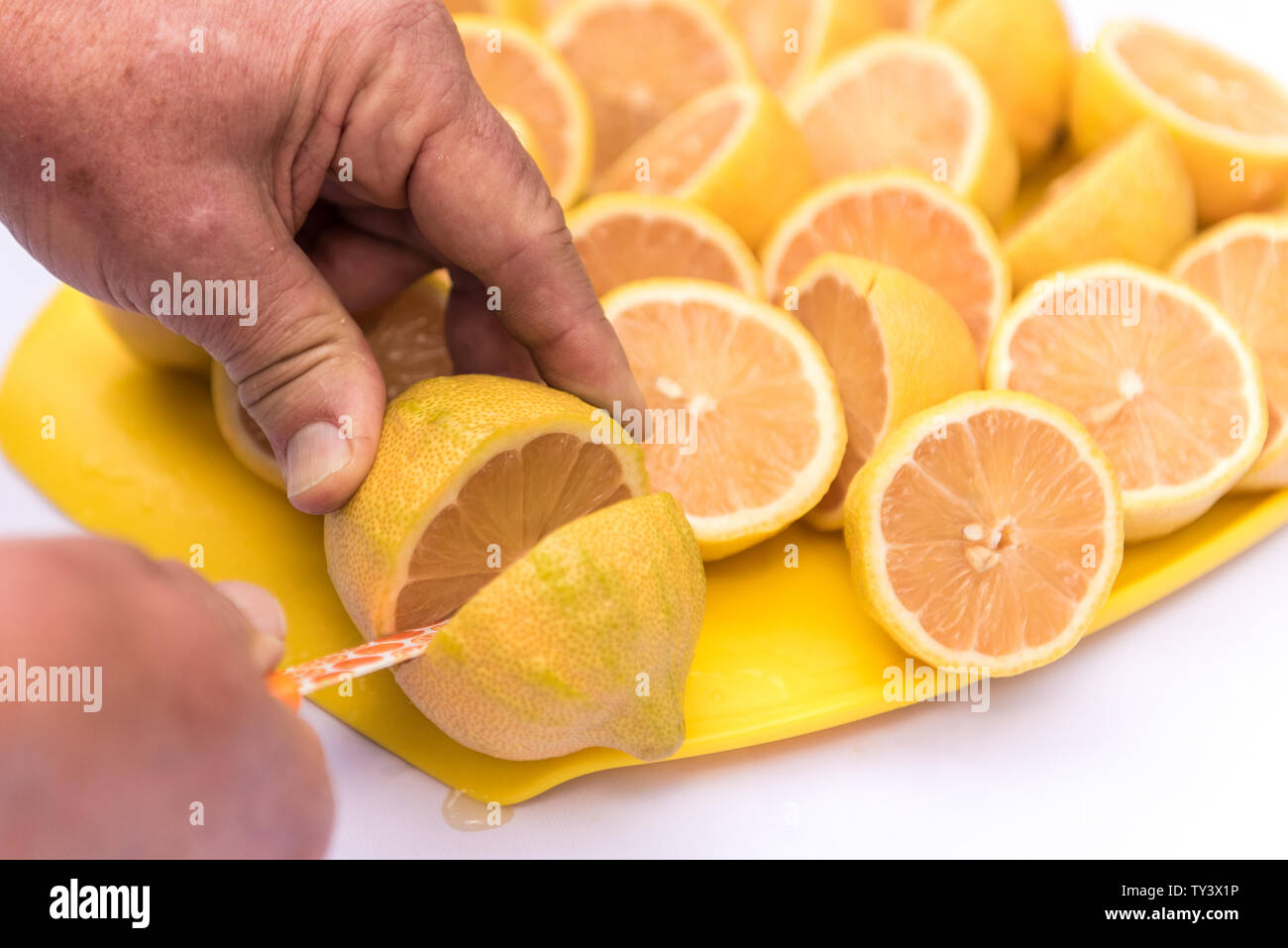 Mani maschili e taglio di servire un piatto di appena raccolto rosa metà di limone. Foto Stock