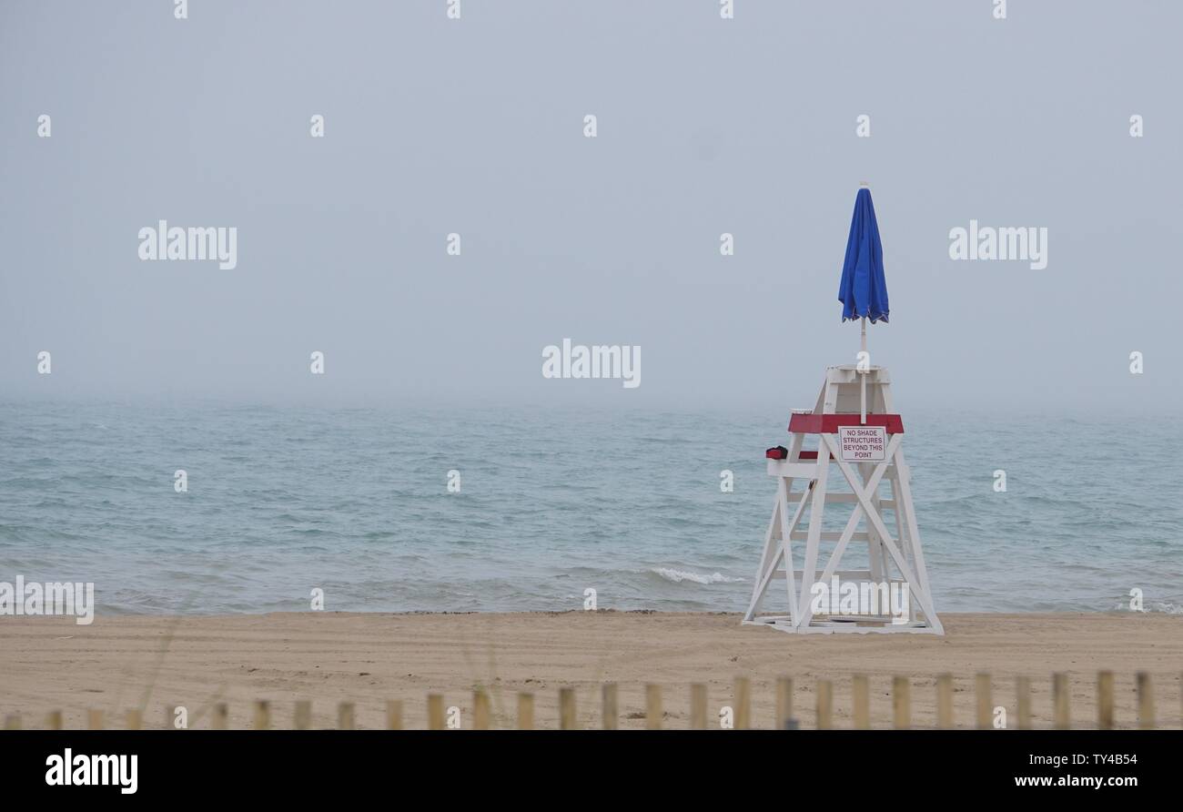 Vuoto sedia bagnino su un lago Michigan spiaggia chiusa a causa della nebbia e freddo Foto Stock