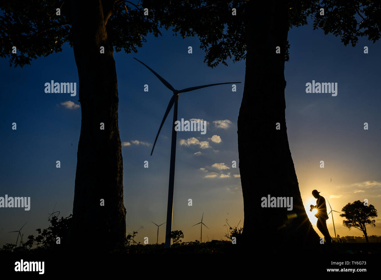 Jeneponto, Indonesia. Il 23 giugno, 2019. Un residente passeggiate passato il turbine di Tolo 1Jeneponto wind energy power plant in Sud Sulawesi.Indonesia ha già due impianti di energia eolica con una capacità totale di 147 MW e il più grande del sud-est asiatico. Credito: SOPA Immagini limitata/Alamy Live News Foto Stock