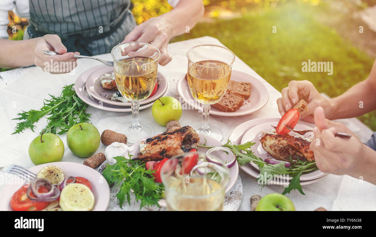 Banner Web. La gente mangia a tavola con vino e grigliate di pesce, verdure fresche e erbe aromatiche. Inquadratura orizzontale Foto Stock