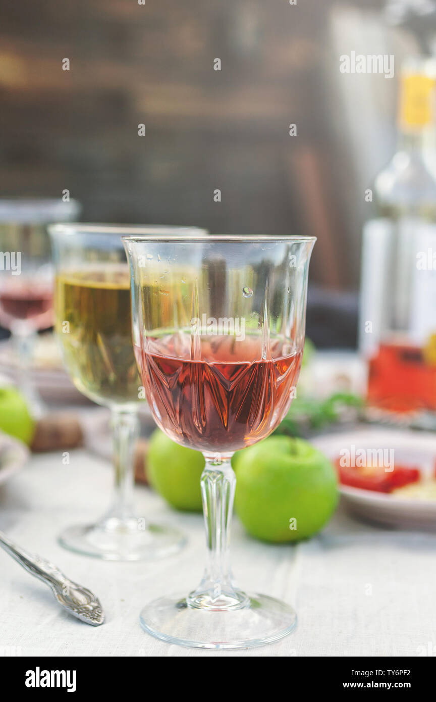 Bicchieri di bianco e vino rosato e grigliate di pesce, verdure, insalate e frutta sul tavolo. Festa estiva nel cortile. Colpo verticale Foto Stock