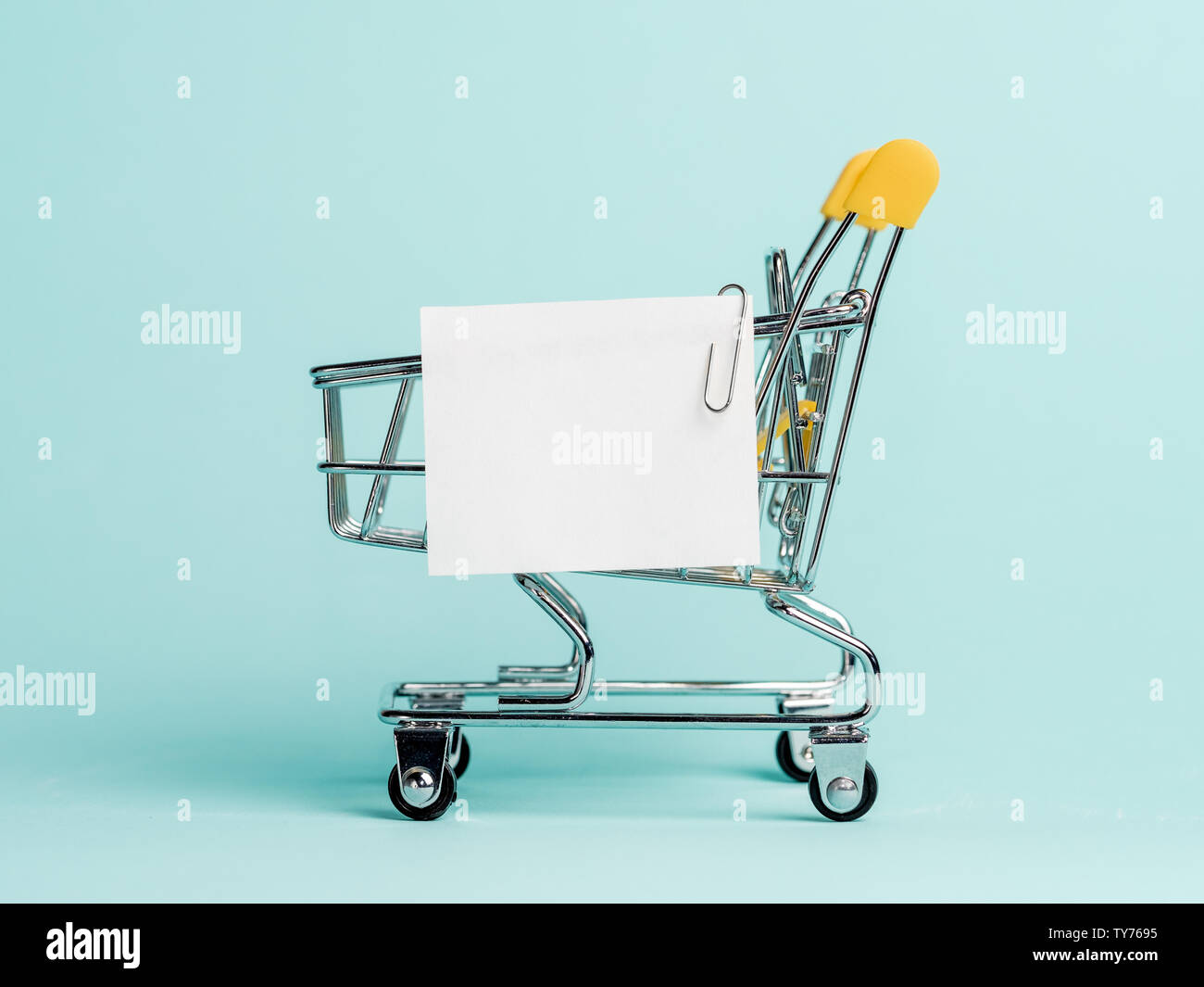 Carrello spesa e white paper nota elenco su sfondo blu. Il concetto di shopping su sfondo blu. Vuoto di carta bianca nota su carrello. Copia spazio per il testo o il design. Foto Stock