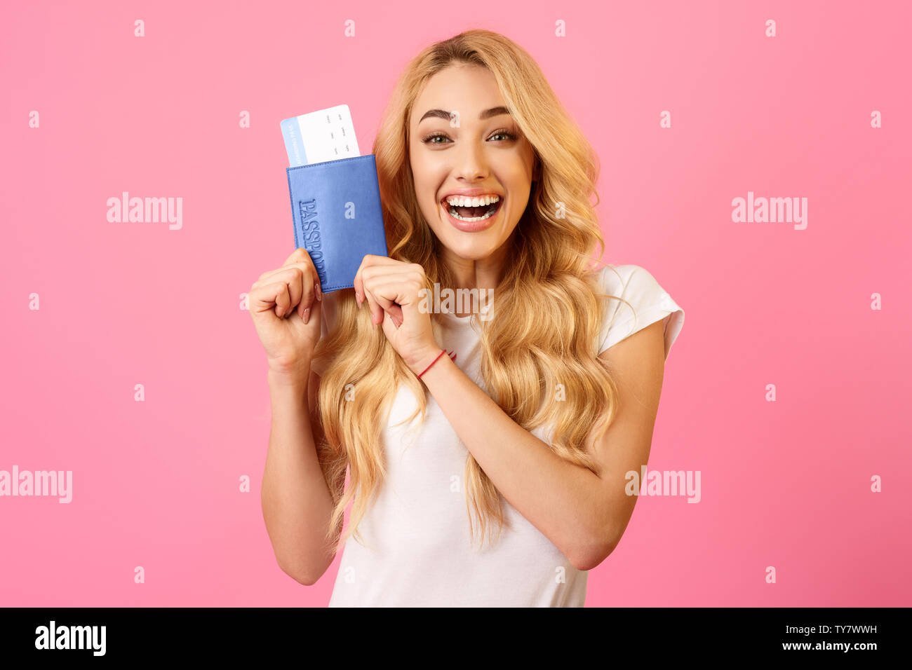 Excited donna in possesso di un biglietto e passaporto, sfondo rosa Foto Stock