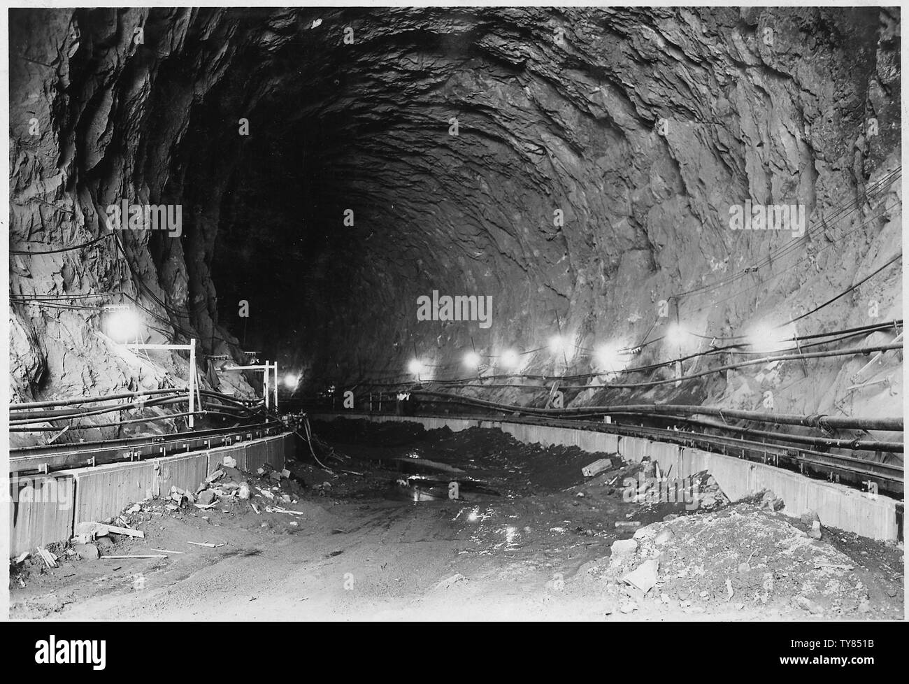 Guardando a valle attraverso il tunnel di deviazione n. 2 dal punto in prossimità del portale di ingresso. Le vie sulle quali gru a portale viaggi quando colata di calcestruzzo invertito sono visibili a destra e a sinistra.; Portata e contenuto: fotografia dal volume due di una serie di album di foto per documentare la costruzione della Diga di Hoover, Boulder City, Nevada. Foto Stock
