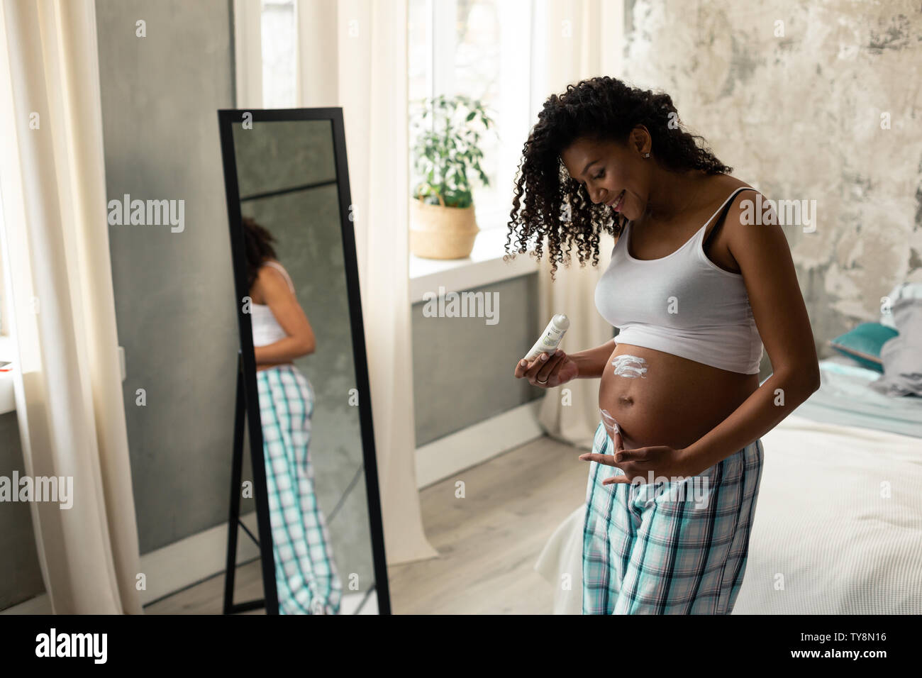 Donna incinta avendo cura della sua pelle della pancia. Foto Stock