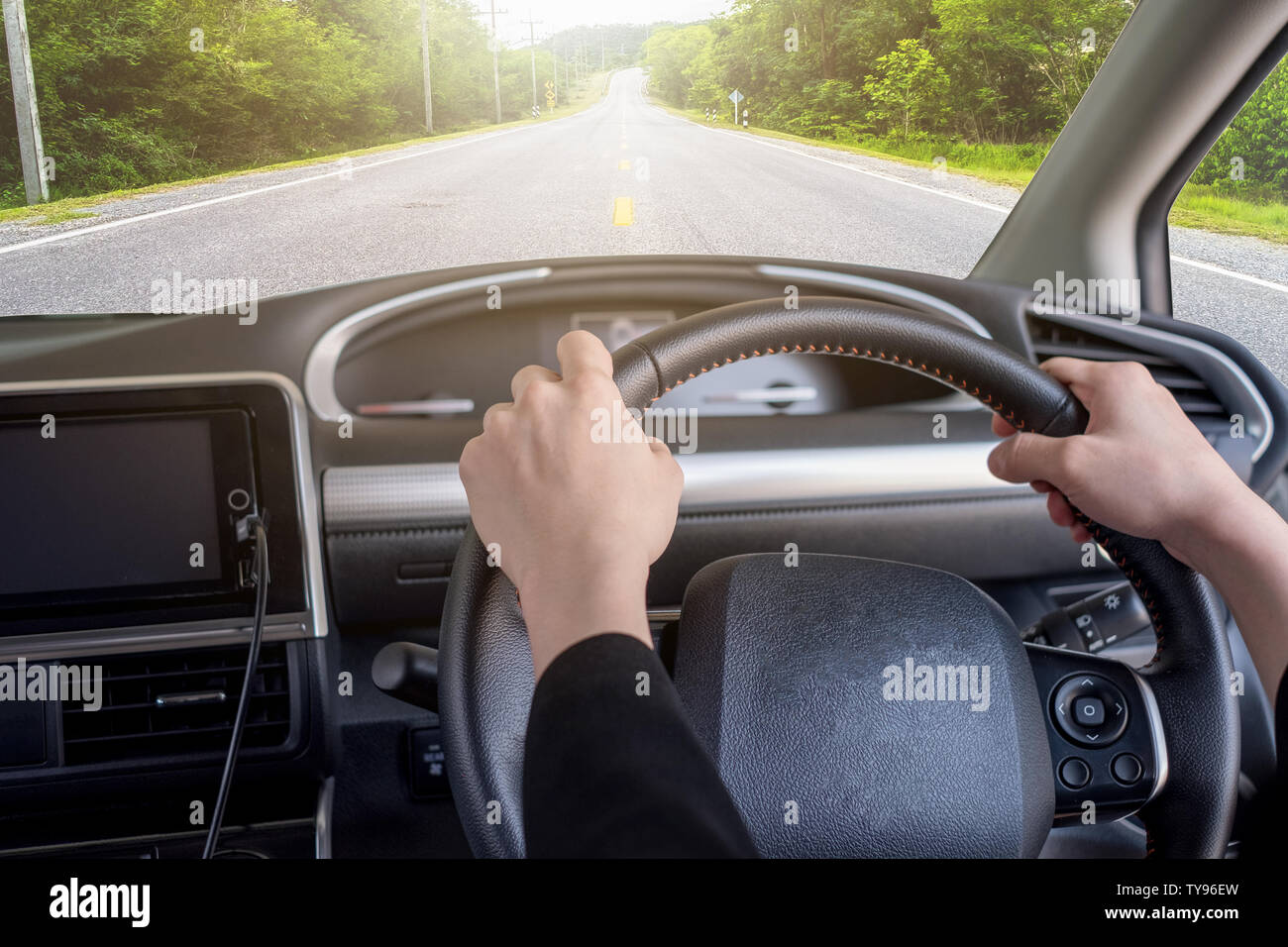 Tenendo la mano destra il volante con autostrada in strada di campagna Foto Stock