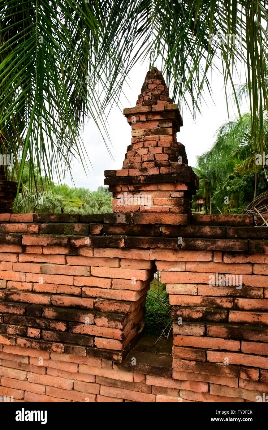 In rosso di un muro di mattoni che circondano un tempio, nella campagna del sud est della Thailandia Foto Stock