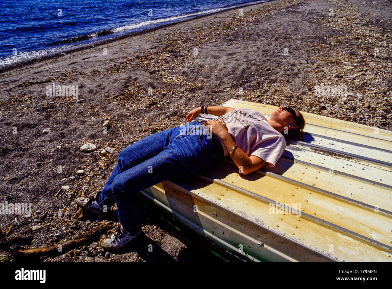Nuova Zelanda, Isola del nord. Tourist in appoggio al sole su una barca capovolta sulla riva del lago Taupo. Foto: © Simon Grosset. Archivio: immagine digitalizzata Foto Stock