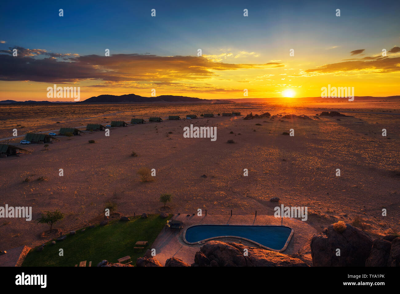 Il tramonto sopra i piccoli chalets di una desert lodge vicino al Sossusvlei in Namibia Foto Stock