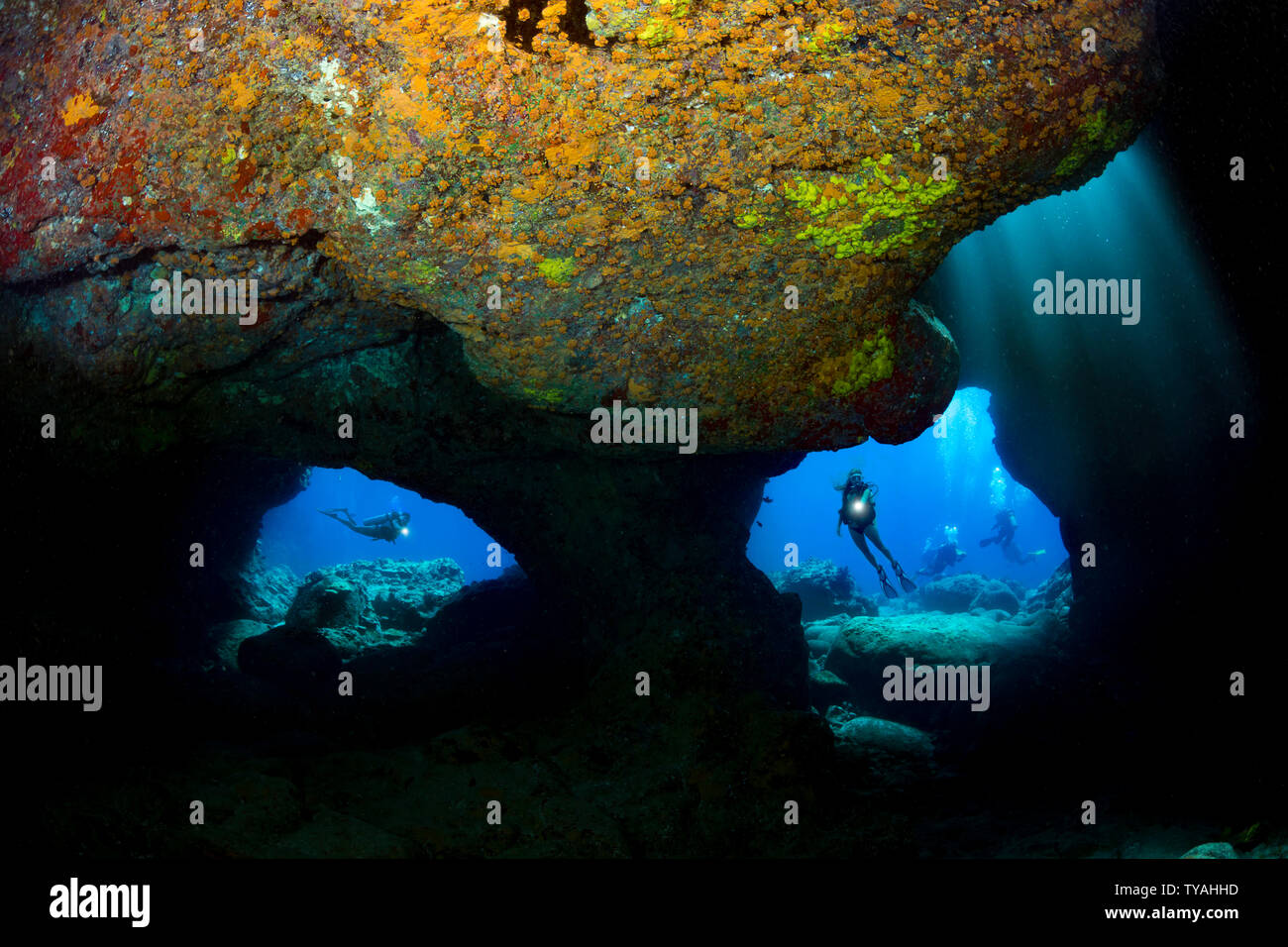 Divers (MR) sono incorniciate dai due aperture in corrispondenza di un sito di immersione conosciuta come Grotta del cranio off Kona Coast della Big Island delle Hawaii. Foto Stock