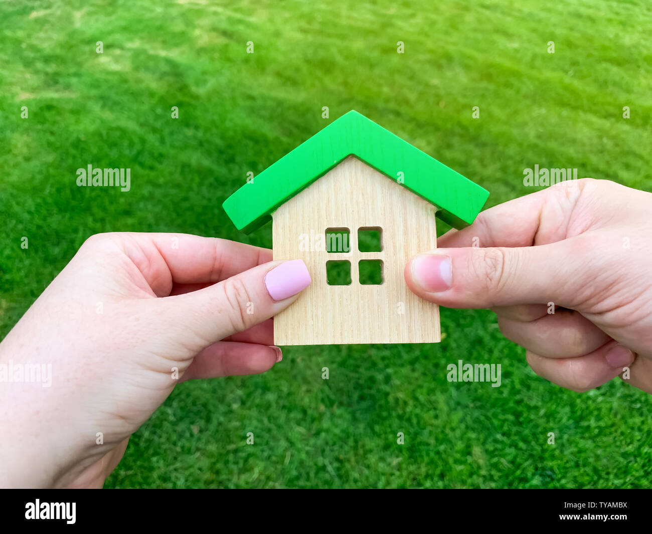 Casa in legno in mano di una giovane famiglia. Acquisto di una casa in un mutuo ipotecario. Immobiliare di concetto. Eco Friendly Home. Il sostegno del governo. Simbolo di ha Foto Stock