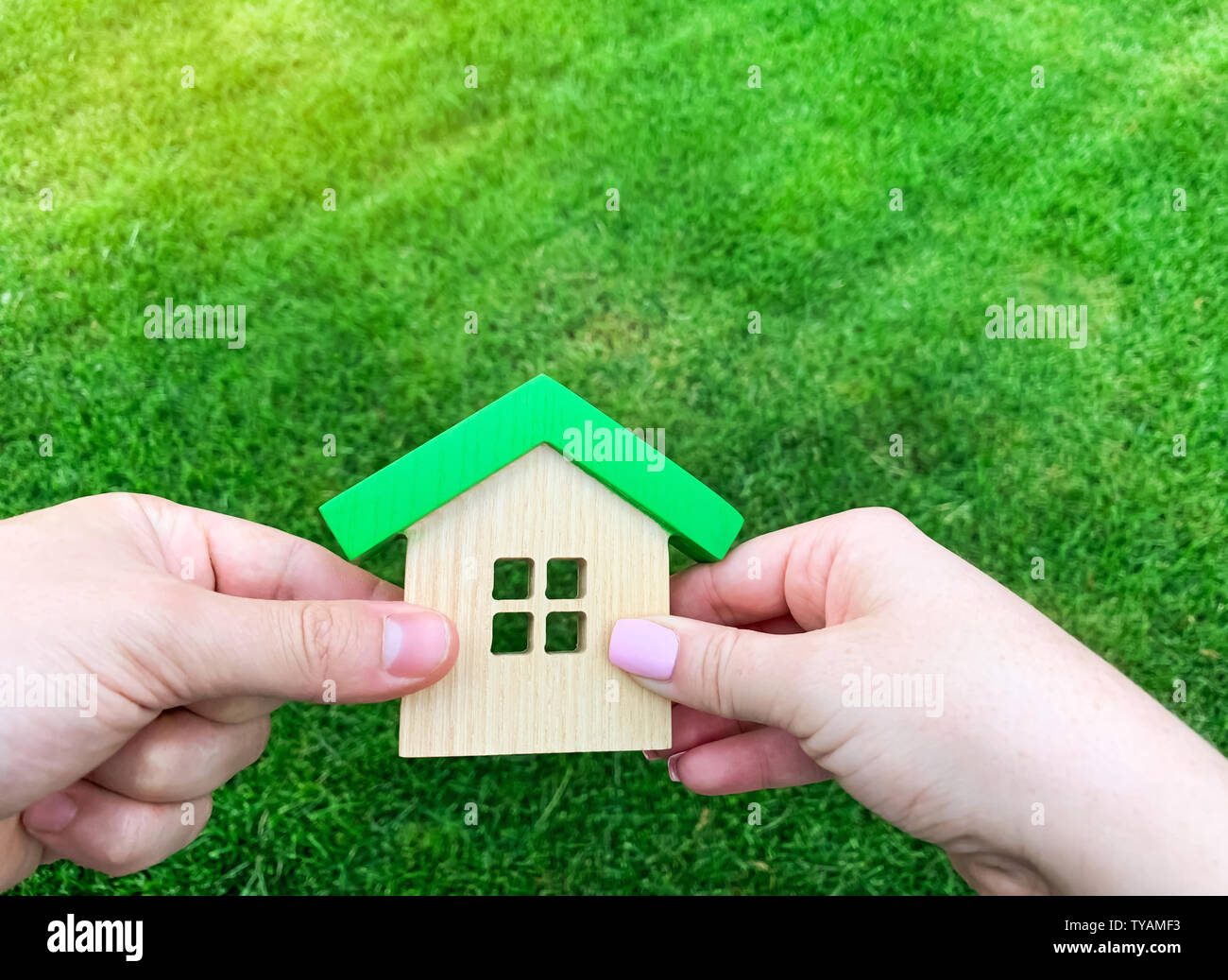 Casa in legno in mano di una giovane famiglia. Acquisto di una casa in un mutuo ipotecario. Immobiliare di concetto. Eco Friendly Home. Il sostegno del governo. Simbolo di ha Foto Stock