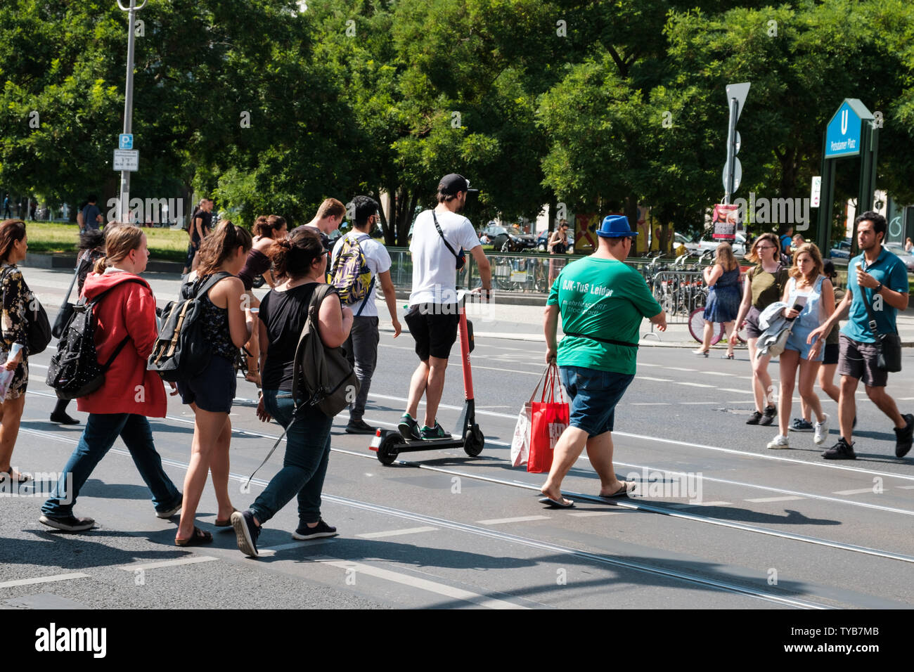 Berlino, Germania - Giugno, 2019: pedoni e un uomo su scooter elettrico , escooter o e-scooter attraversando via Foto Stock