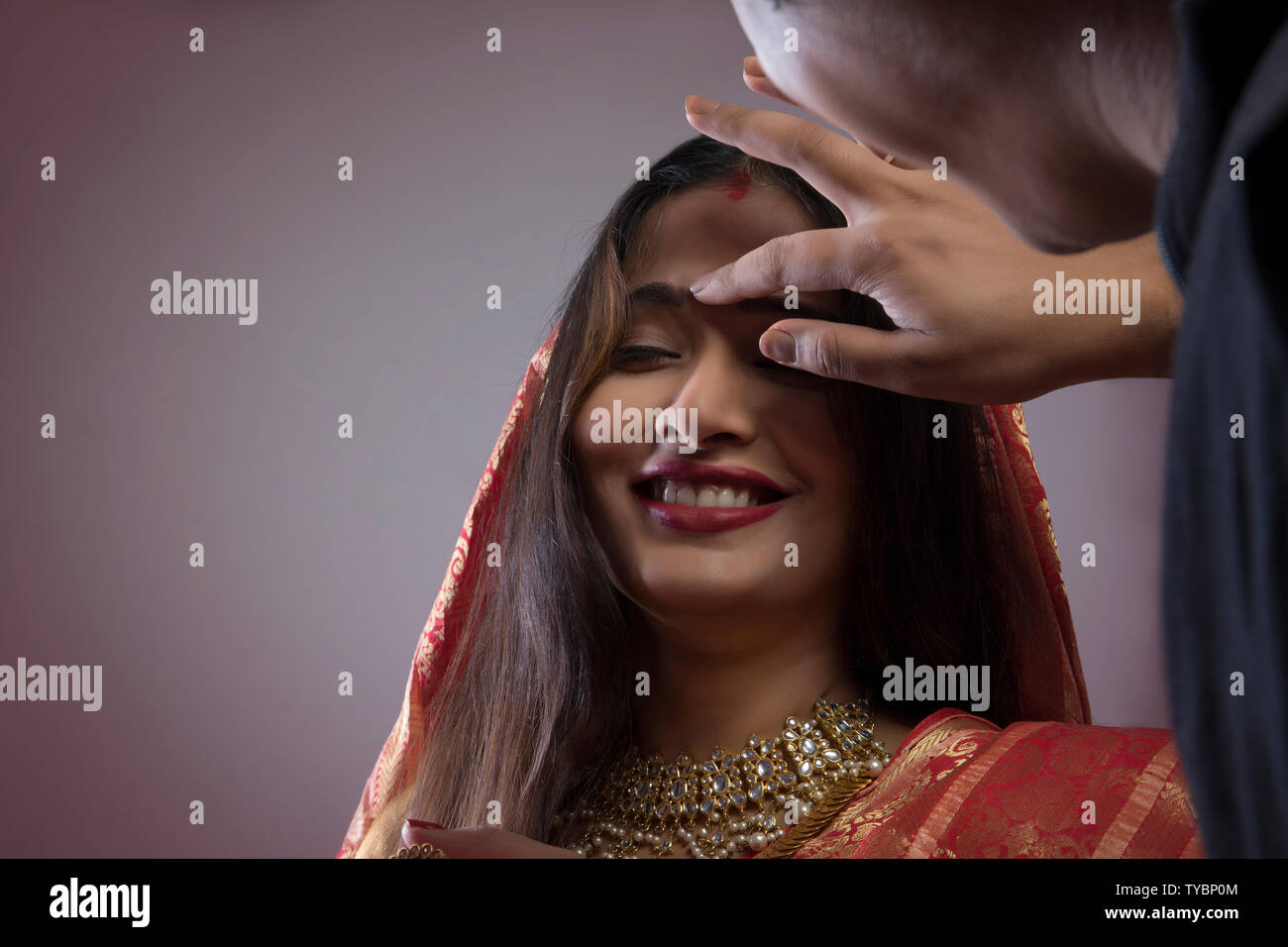 Uomo in Bengali mettendo sindoor sulla moglie di fronte Foto Stock