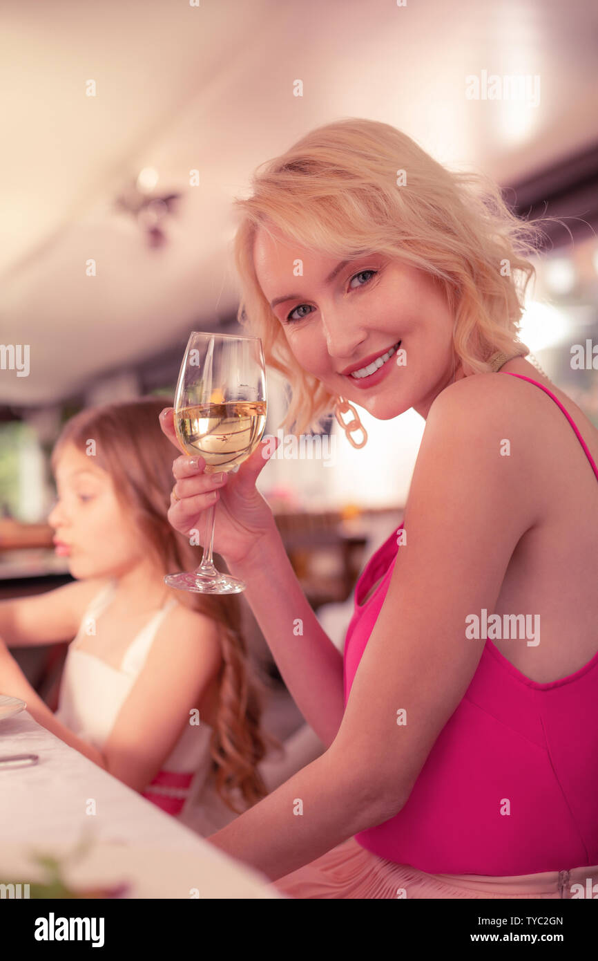 Donna che mantiene un bicchiere di champagne mentre è seduto vicino a figlia Foto Stock