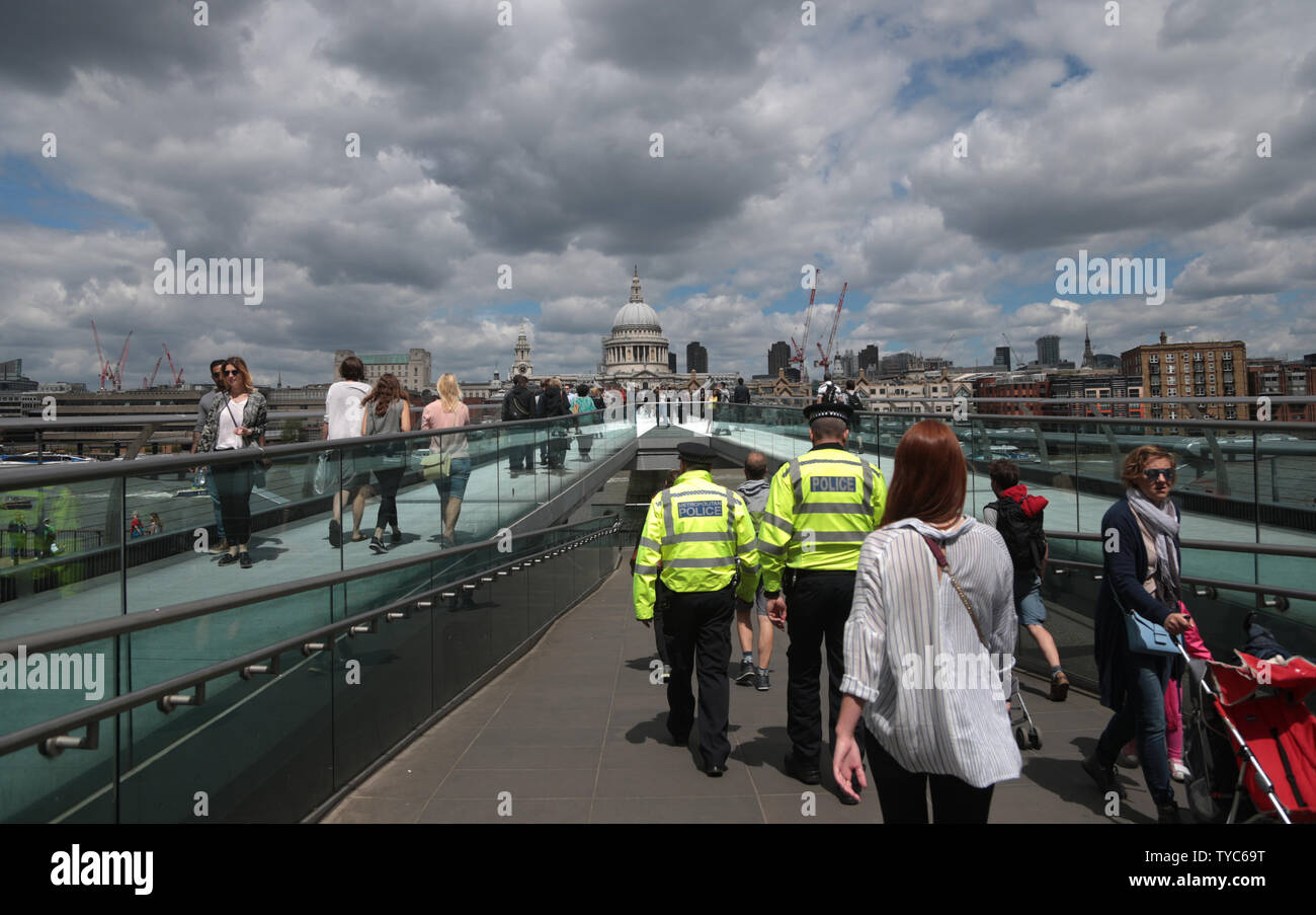 I funzionari di polizia sul Millennium bridge si mescolano con i membri del pubblico nei pressi del luogo in cui la notte scorsa tre terroristi ha ucciso sette persone e il ferimento di 48 dopo aver guidato un furgone a pedoni e commettendo un coltello delirante atack nel vicino mercato di Borough, 04 giugno 2017. La polizia forensics ufficiali continuano a cercare prove nella zona e grandi parti di Londra rimane bloccato su OFF. UPI foto/Hugo Philpott Foto Stock